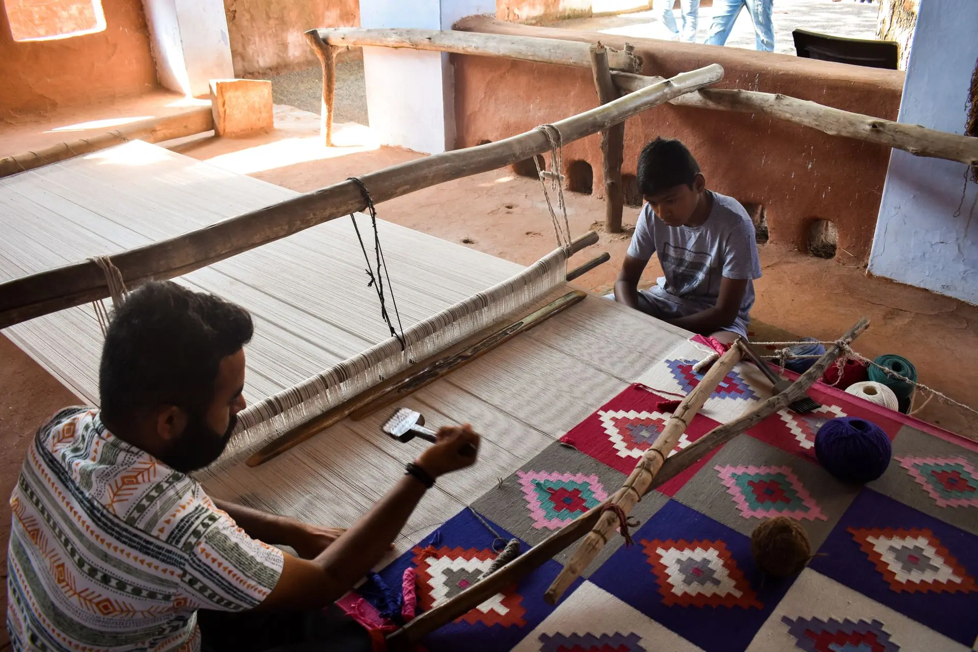 Artisan and child weaving a colorful carpet on a handloom in Jodhpur, Rajasthan
