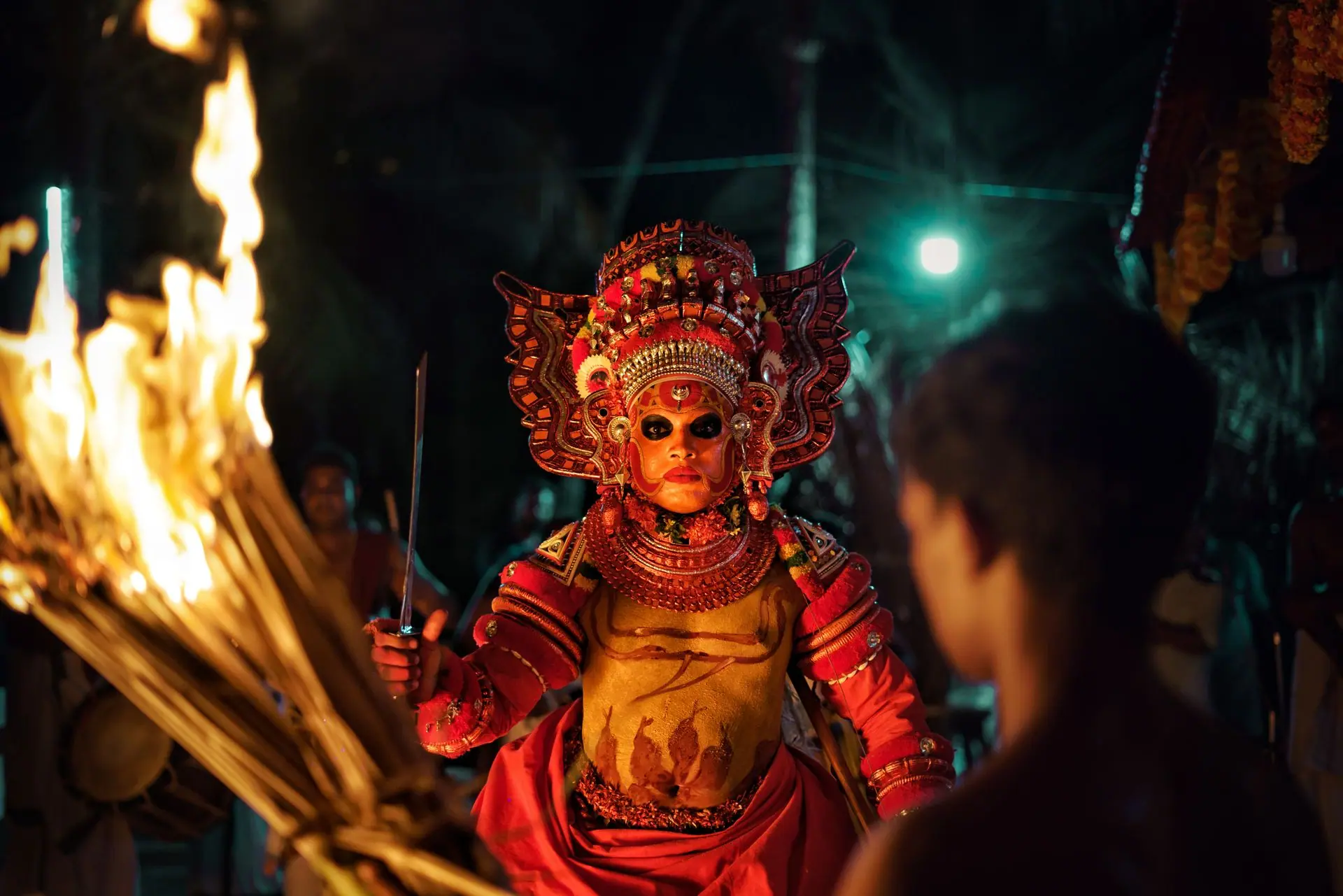 Captivating image of a traditional Theyyam performer with fire in a night festival setting