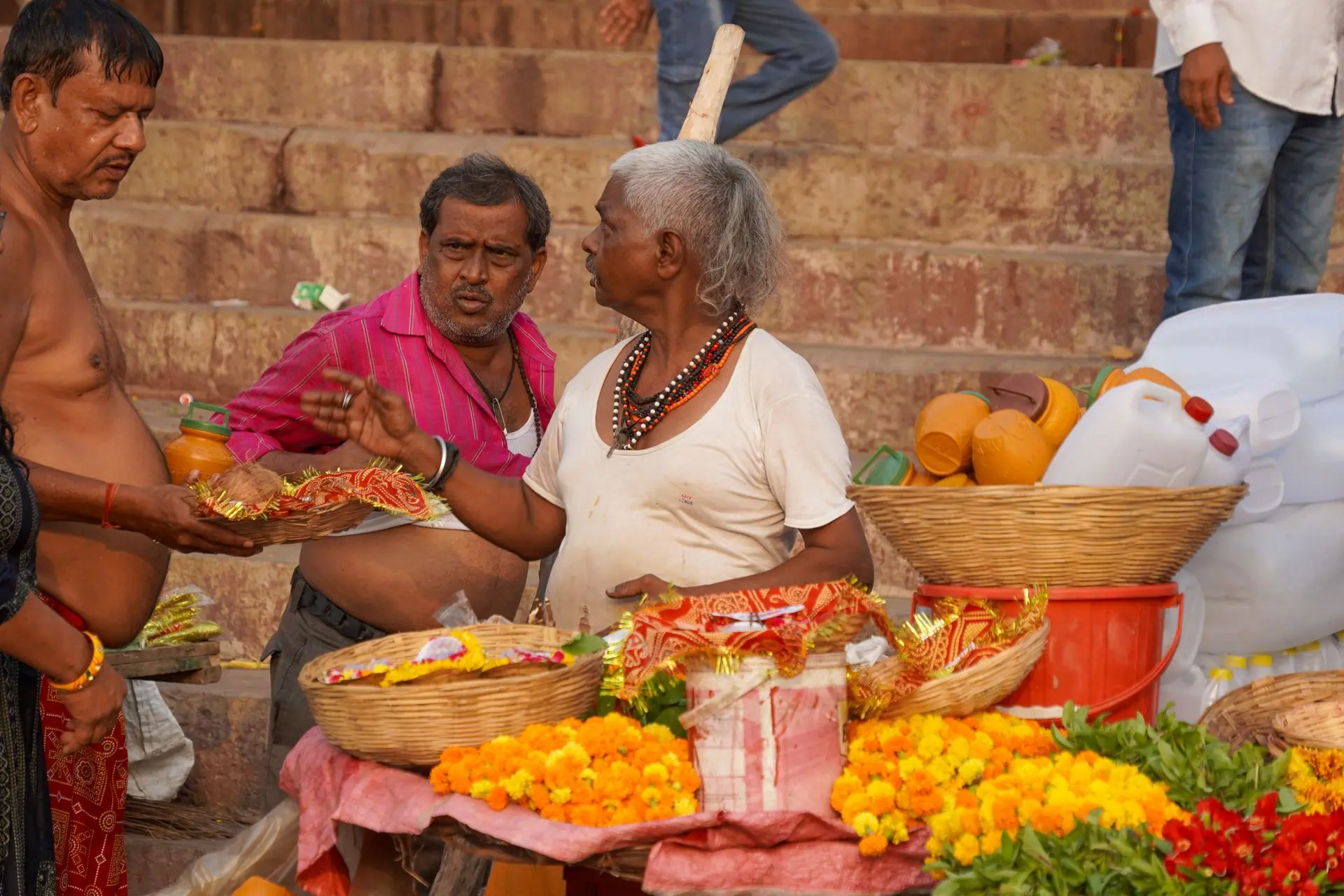 Local vendors at Varanasi Ghats selling vibrant marigolds and offerings. A lively scene of traditional commerce