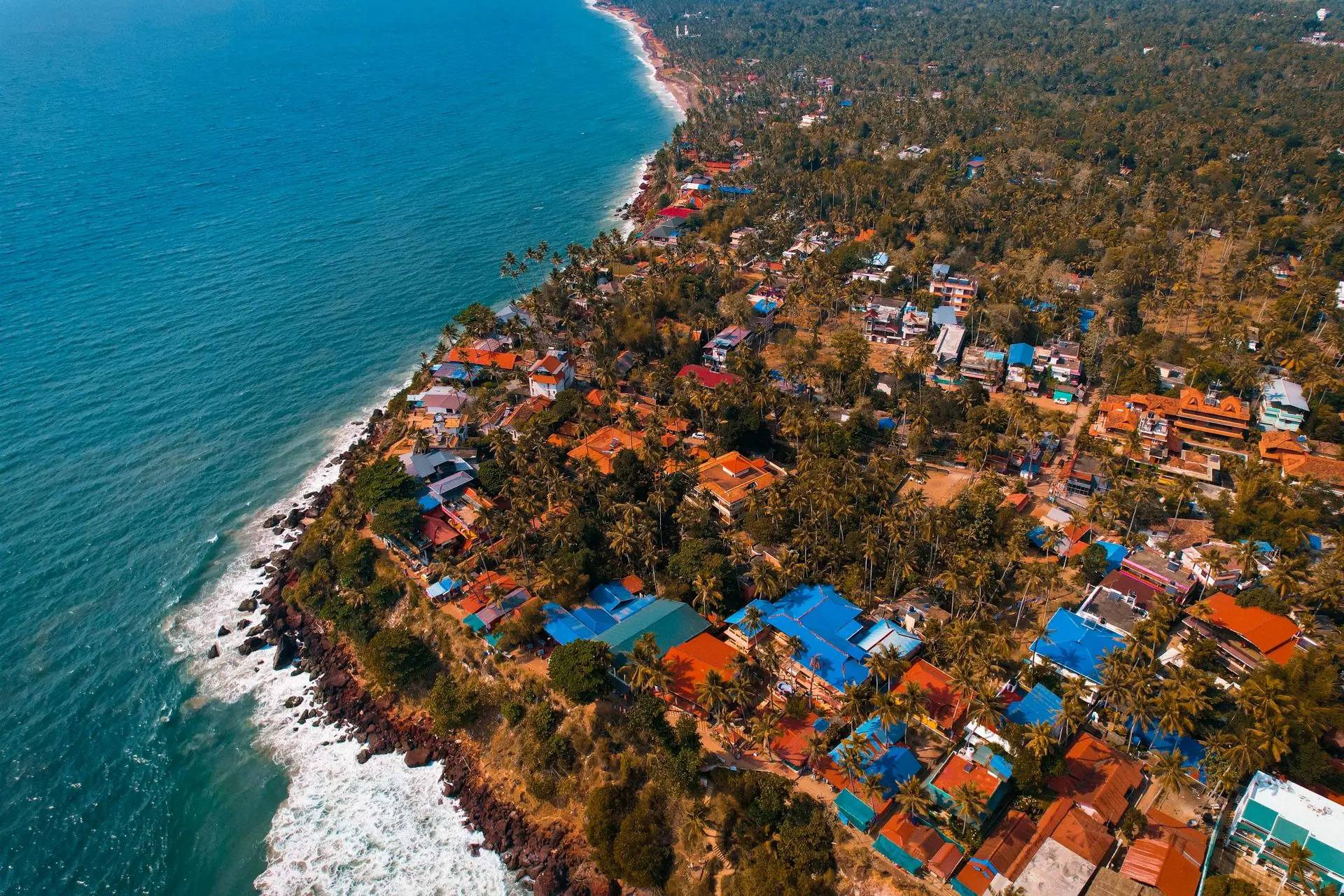 Scenic aerial shot of Varkala, a vibrant coastal village in Kerala, India, showing colorful houses and the Arabian Sea coastline