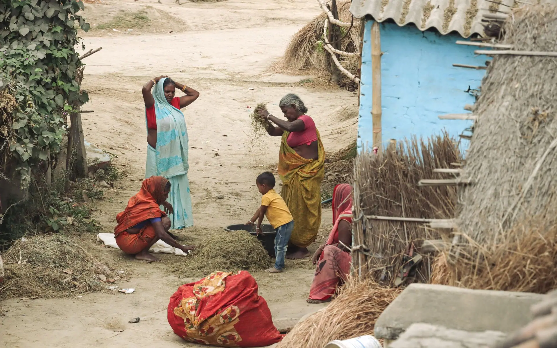 Traditional rural life in an Indian village showing women and a child engaged in farm work