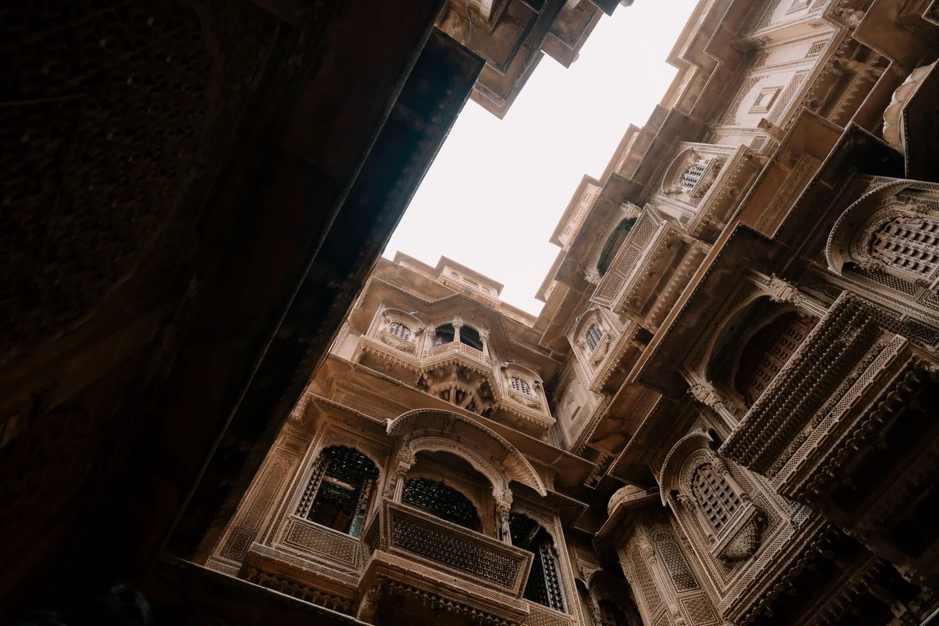 Low-angle view of intricately carved architecture in a historic Jaisalmer haveli, showcasing stunning craftsmanship