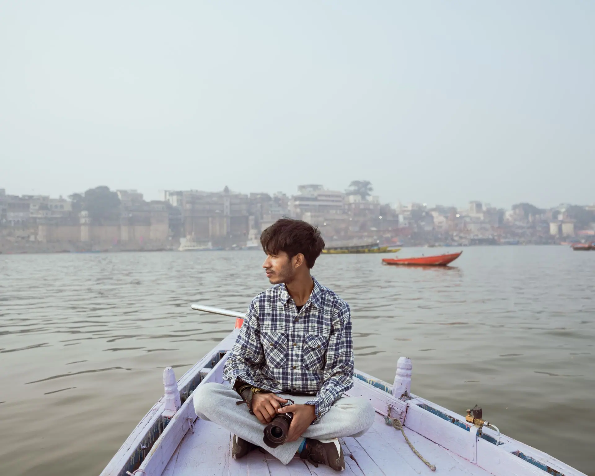 A thoughtful man sits on a boat in Varanasi, India, capturing the serene Ganges River