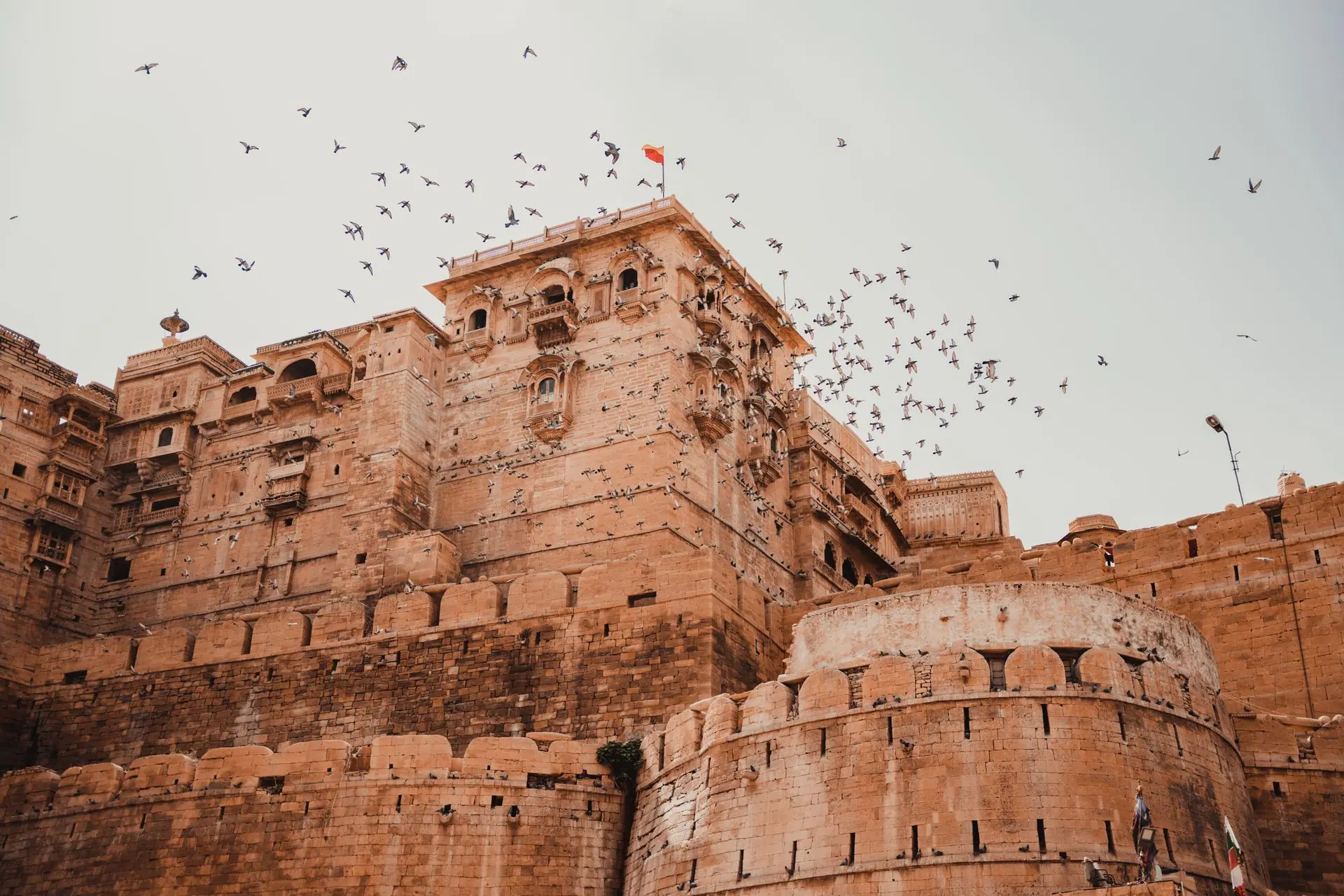 A stunning view of Jaisalmer Fort with birds soaring in the clear sky, epitomizing architectural grandeur