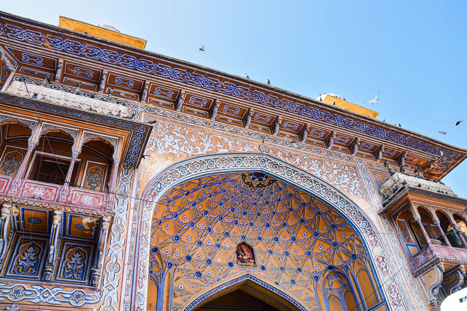 Detailed view of ornate architecture on a historic gate in Jaipur, showcasing vibrant colors and patterns