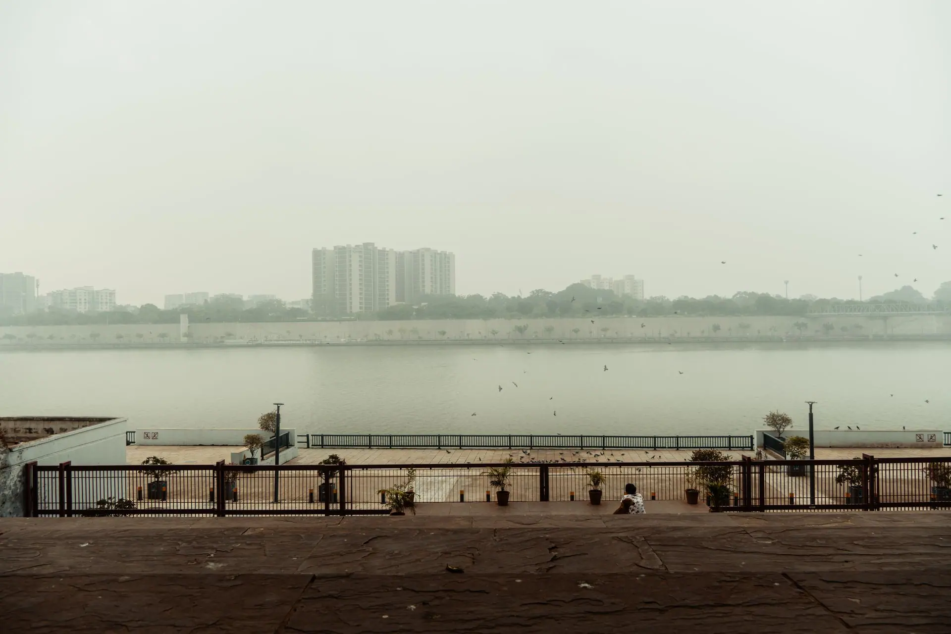 Scenic view of Ahmedabad's river promenade with smog overhead, showcasing urban architecture