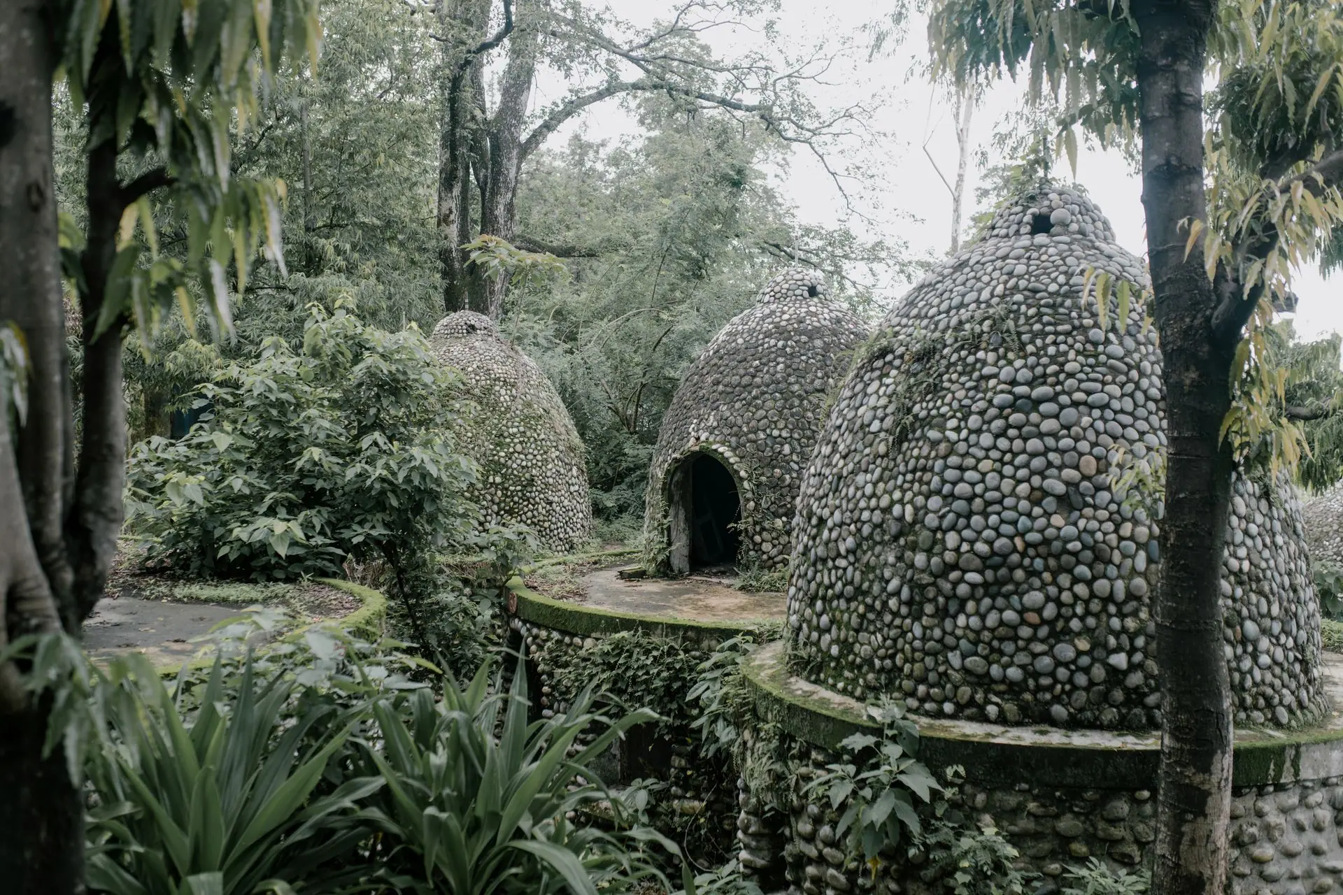 Exterior of aged stone meditation caves located on territory of Beatles Ashram in lush green tropical garden in India