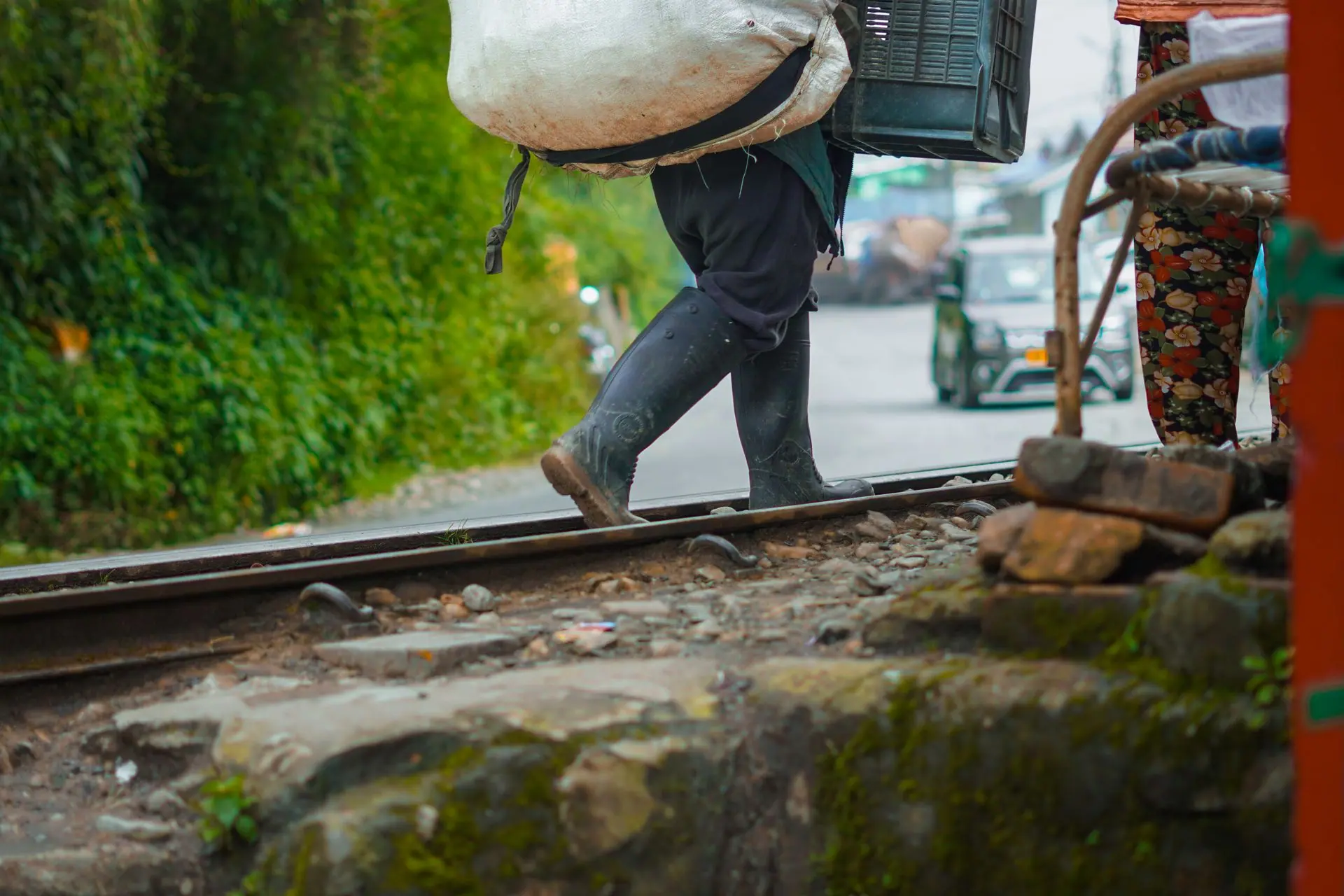 A person walking along railway tracks carrying bundles in Darjeeling, India
