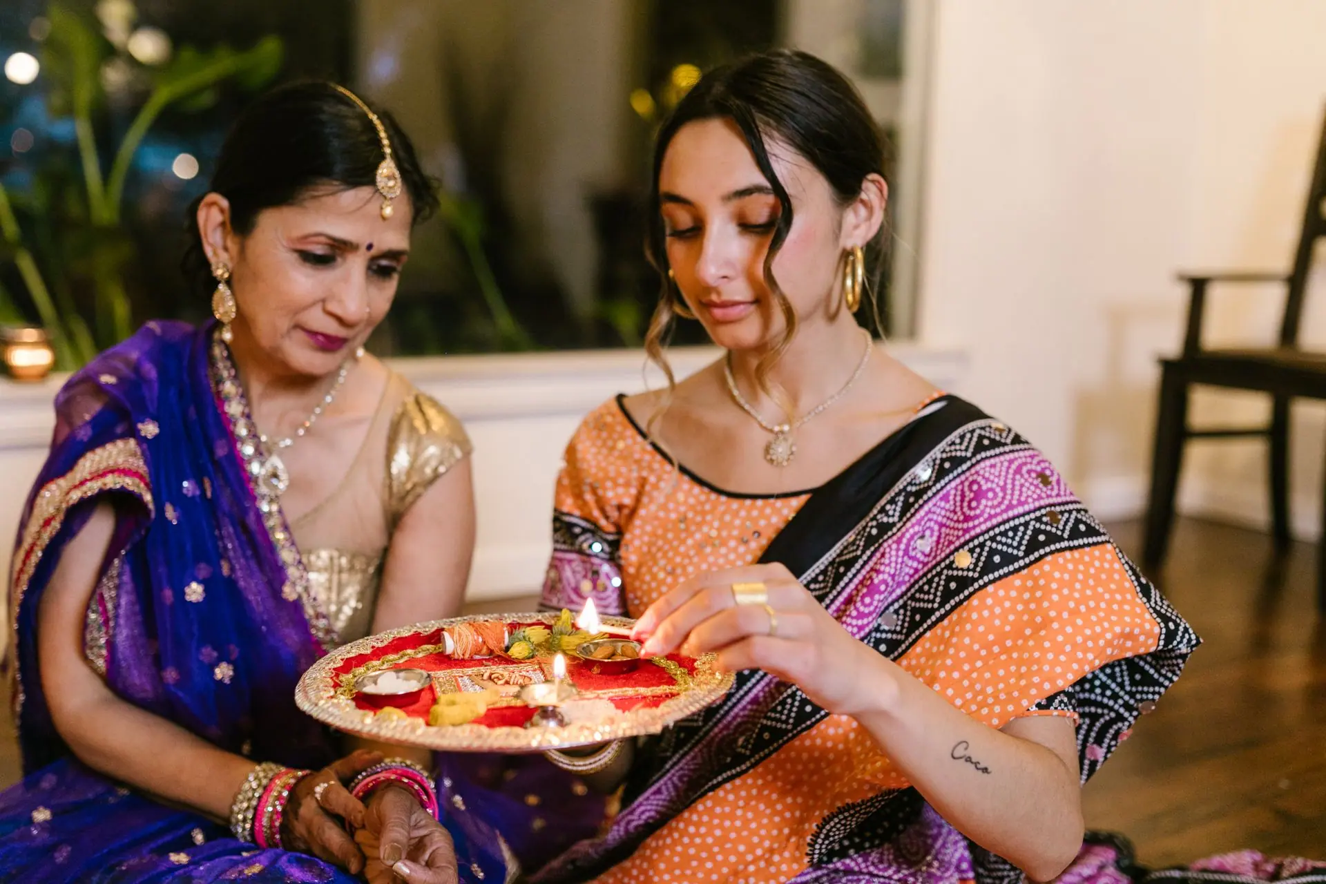 Mother and daughter performing a Diwali ritual with a lit puja plate, showcasing traditional Indian culture