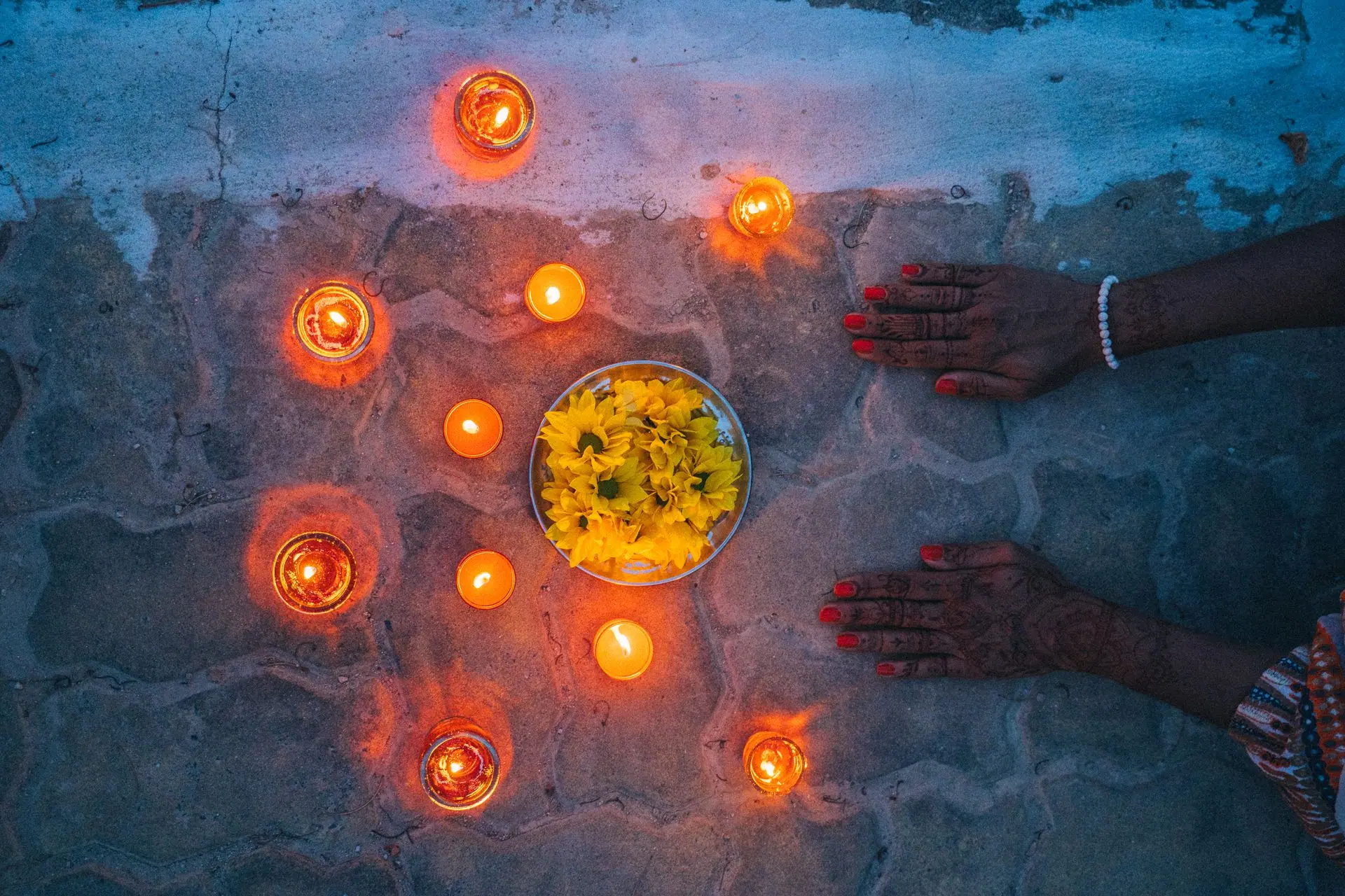 Hands decorated with henna around candles and flowers during Diwali celebration in India