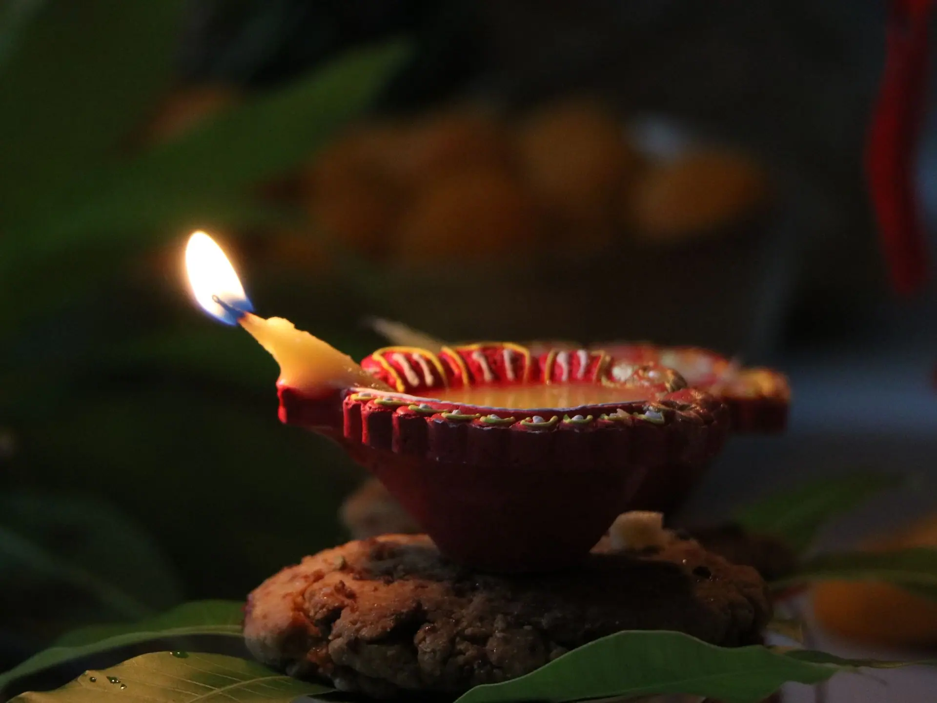 A beautifully lit diya candle on leaves, symbolizing Diwali celebration in India