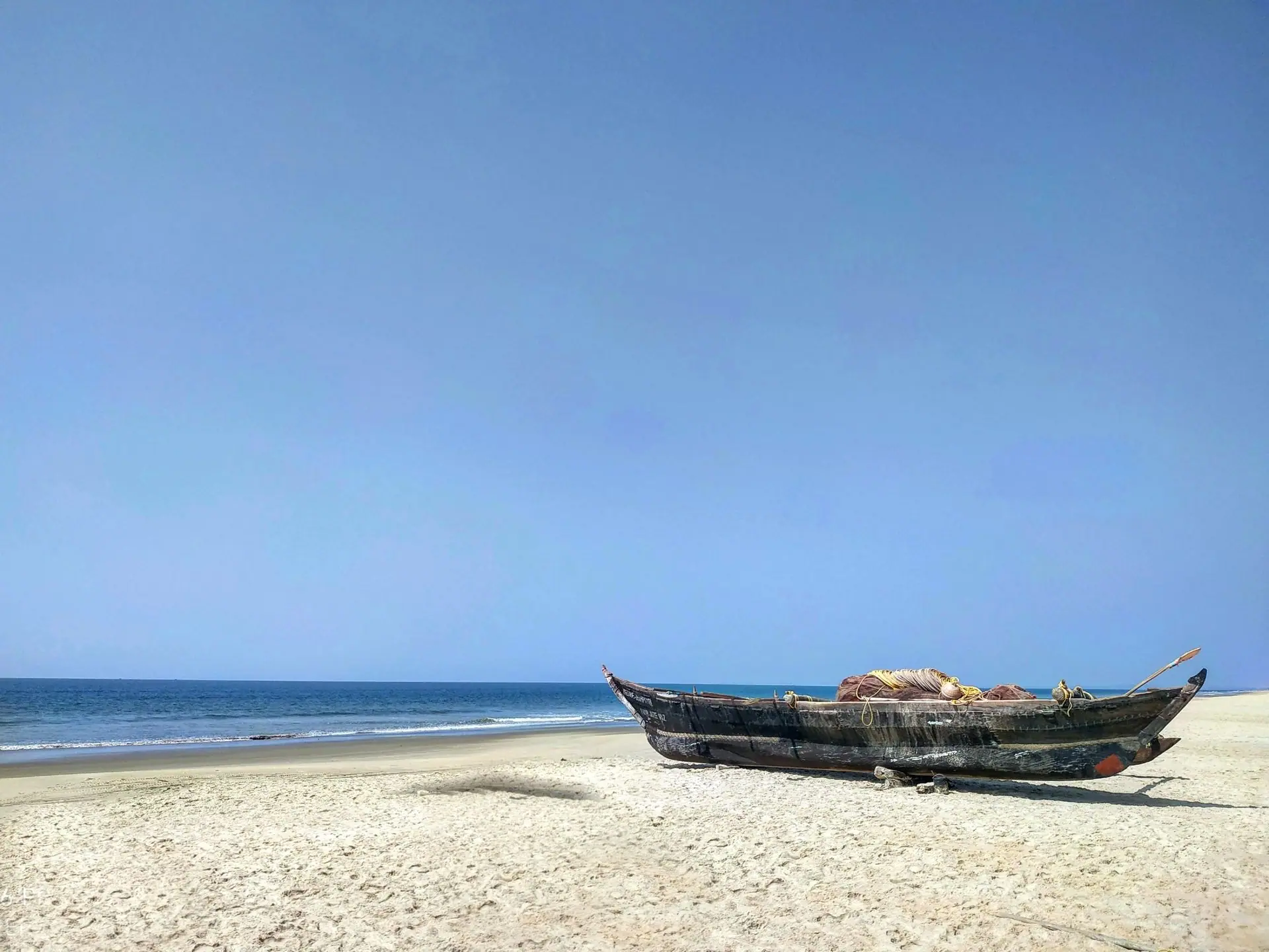Idyllic beach scene in Goa, India with a wooden fishing boat and calm sea