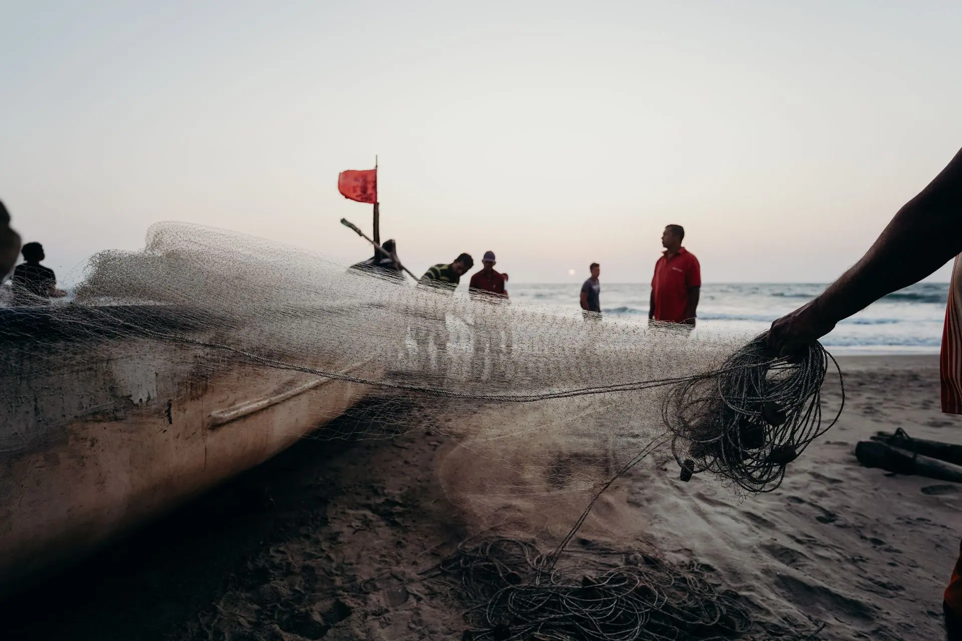A group of fishermen preparing their nets on a beach in Goa at sunset, capturing a traditional scene