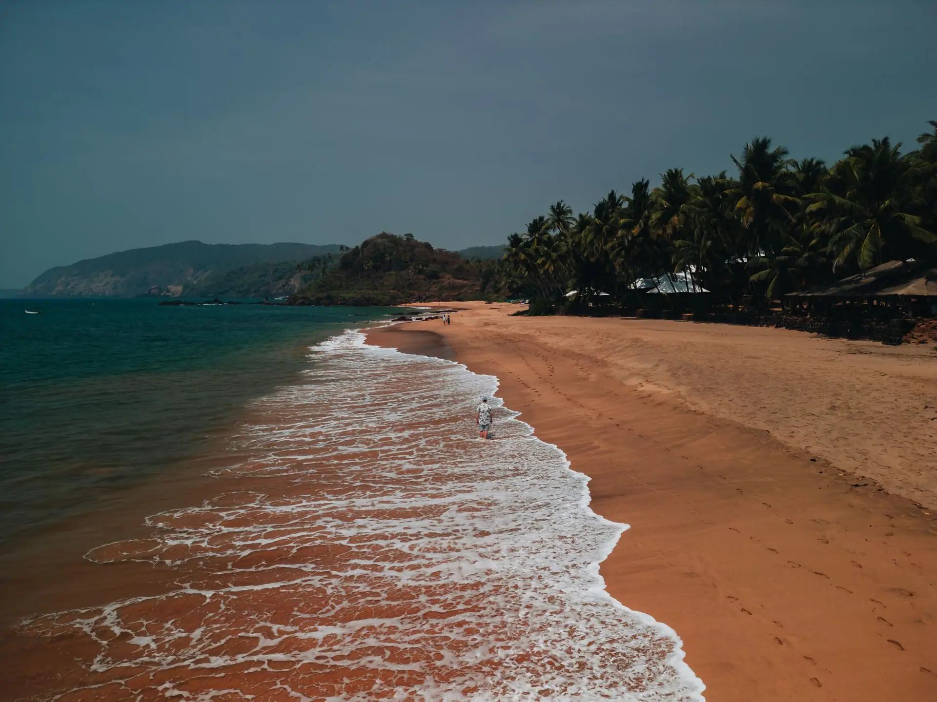 A picturesque aerial view of a serene beach in Goa with golden sands and gentle waves during sunset