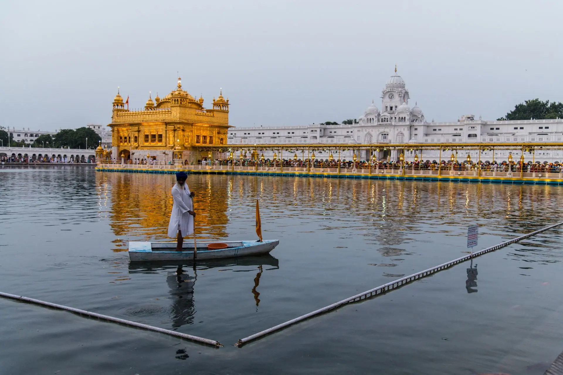 Sikh man on boat in front of the illuminated Golden Temple in Amritsar