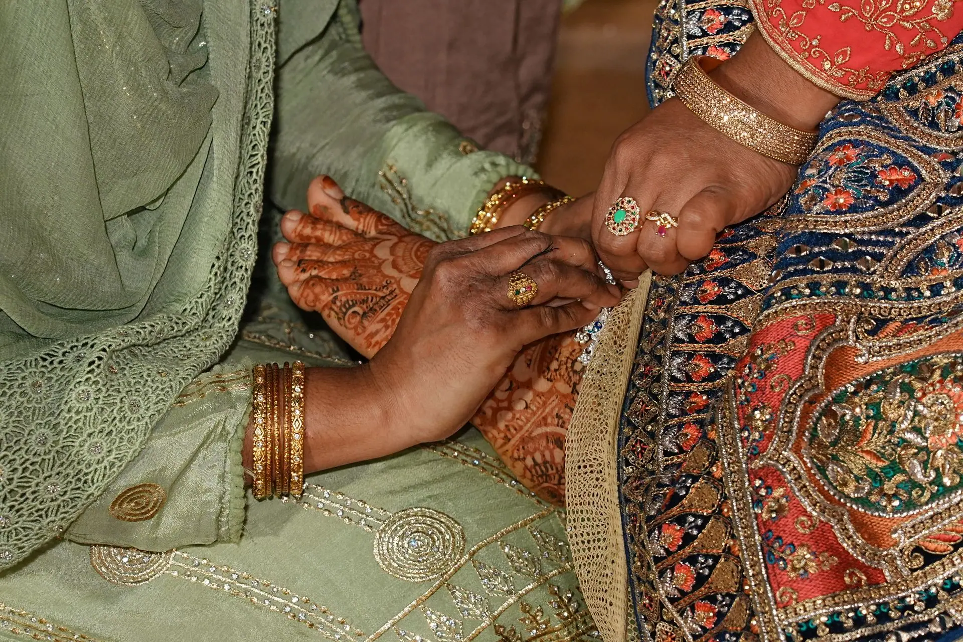 Closeup of traditional Indian wedding mehndi ceremony showcasing intricate henna designs and colorful attire