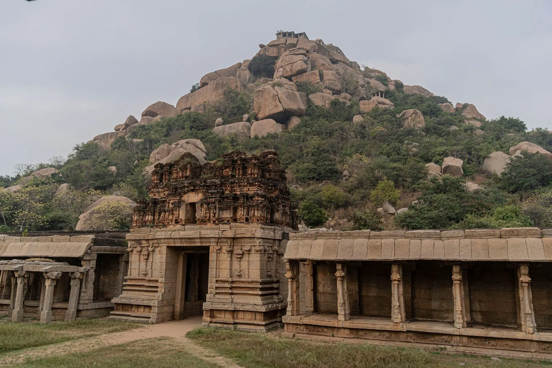 Explore the ancient stone temple ruins at Hampi, showcasing historic architecture against rocky hills