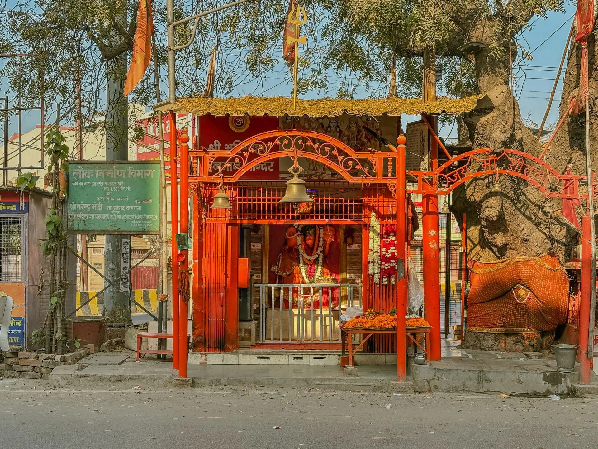 Brightly colored Hanuman temple amidst trees in Varanasi, India, capturing traditional architecture
