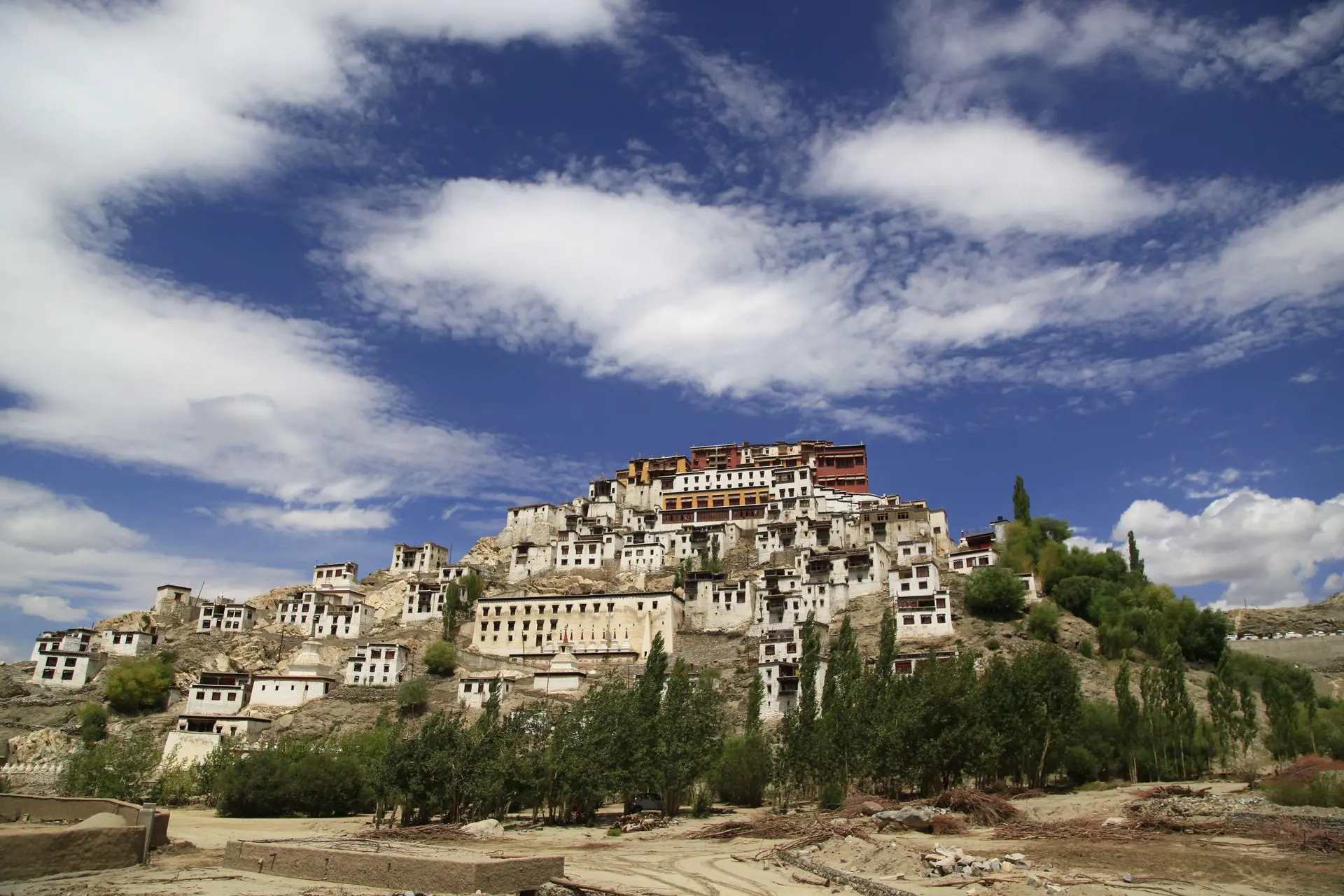 Panoramic view of a historic monastery in Ladakh, showcasing ancient architecture against a vibrant sky