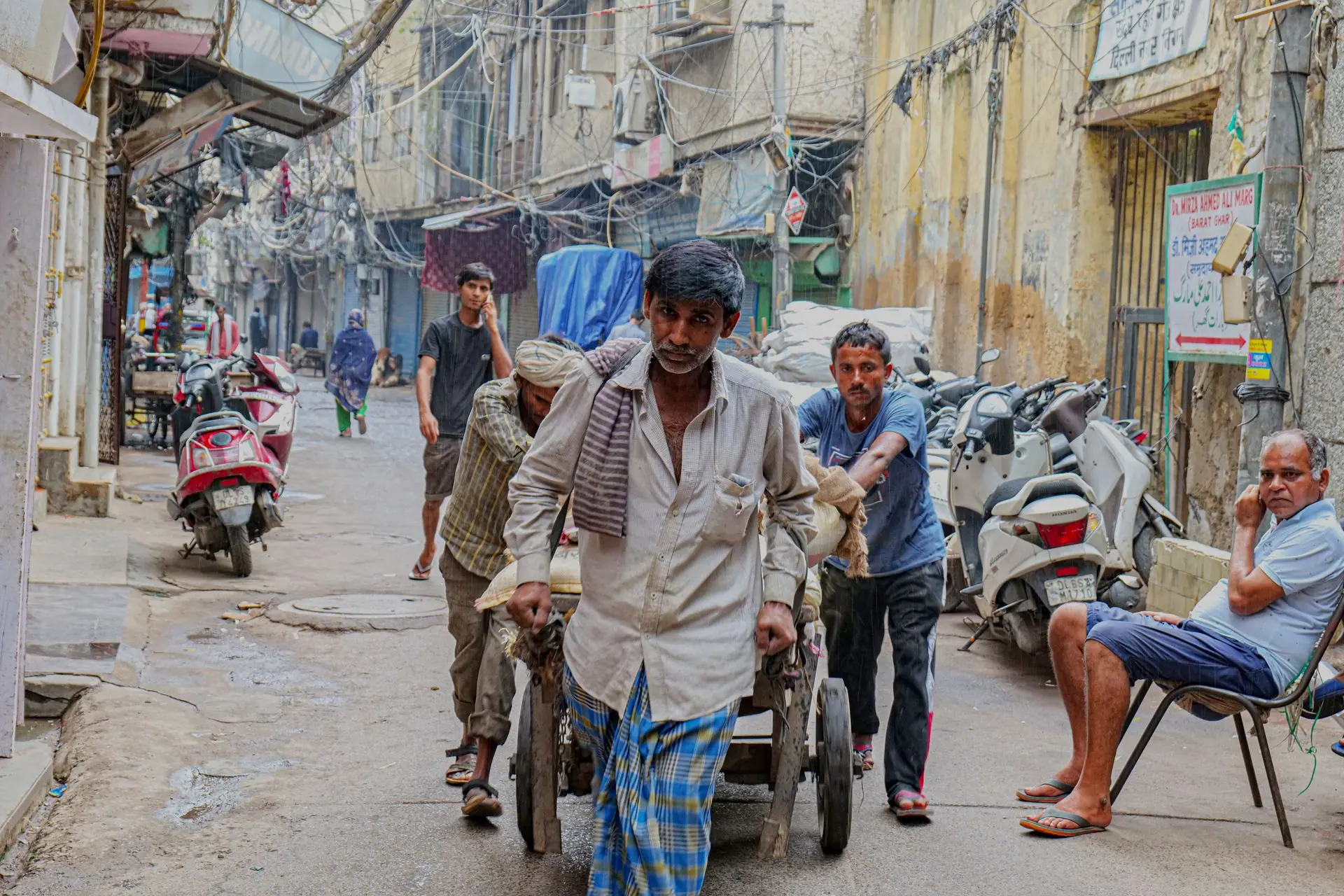 Candid capture of street workers pushing a cart in the bustling streets of Old Delhi, India