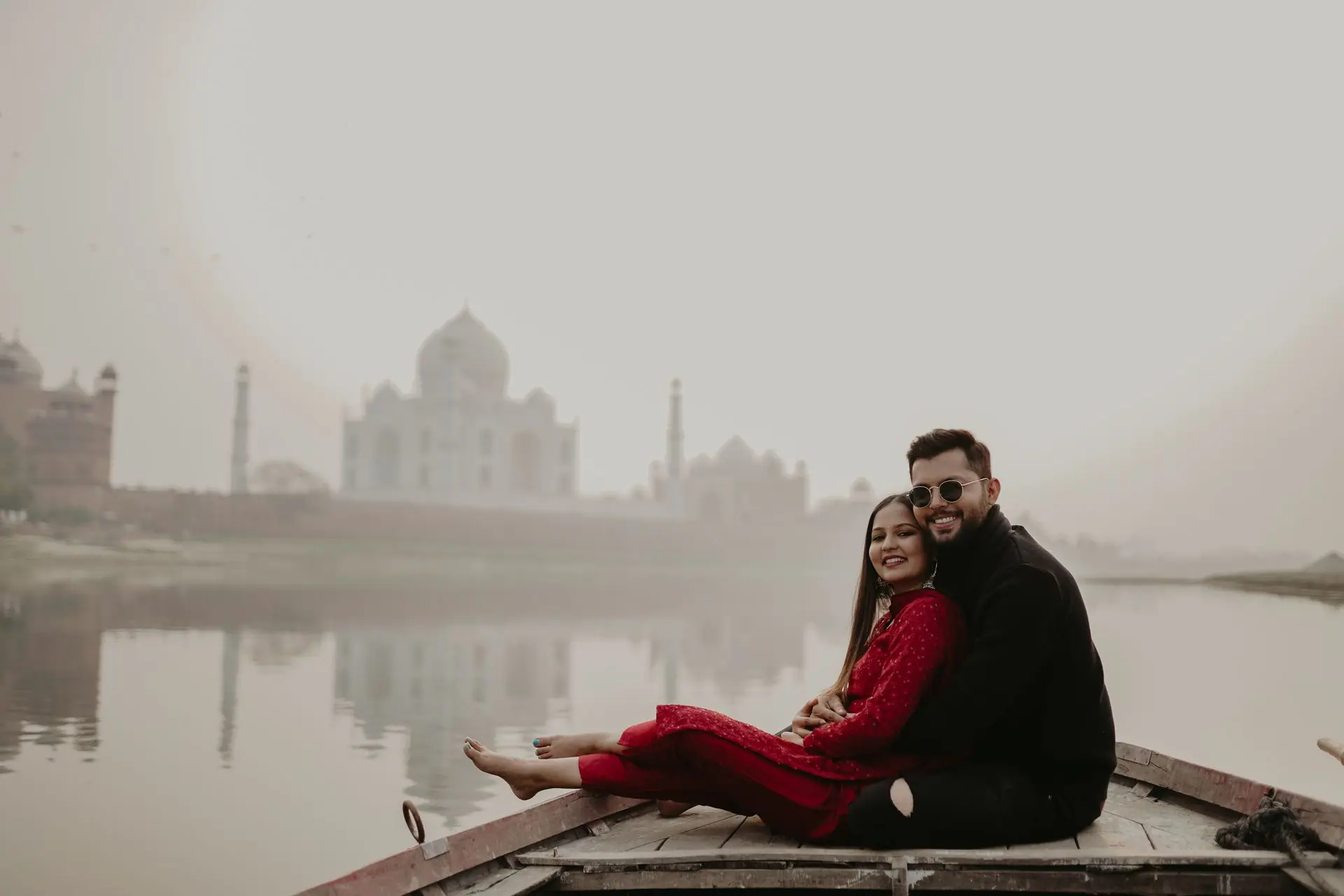 A couple enjoying a serene boat ride with the Taj Mahal in the backdrop, reflecting on the calm river