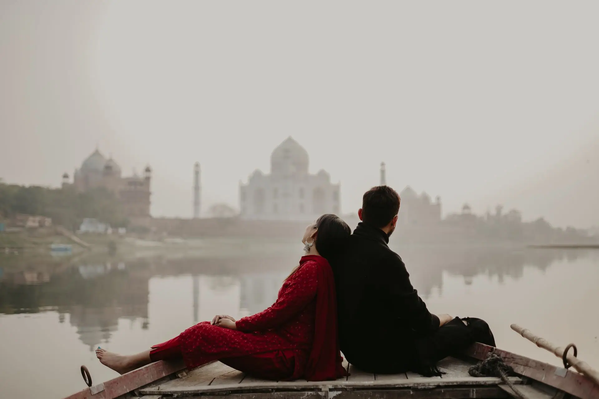 A couple sitting on a boat with the iconic Taj Mahal in the background, evoking a romantic and serene mood