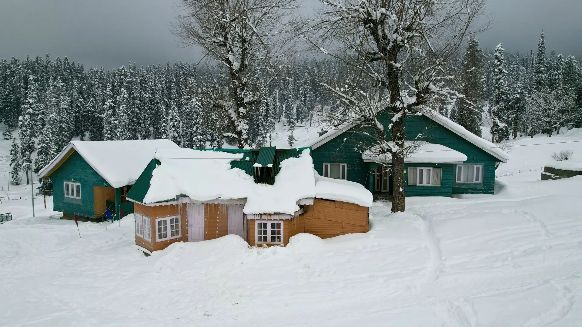 Stunning winter scene in Gulmarg, featuring snow-covered wooden cabins and pine trees