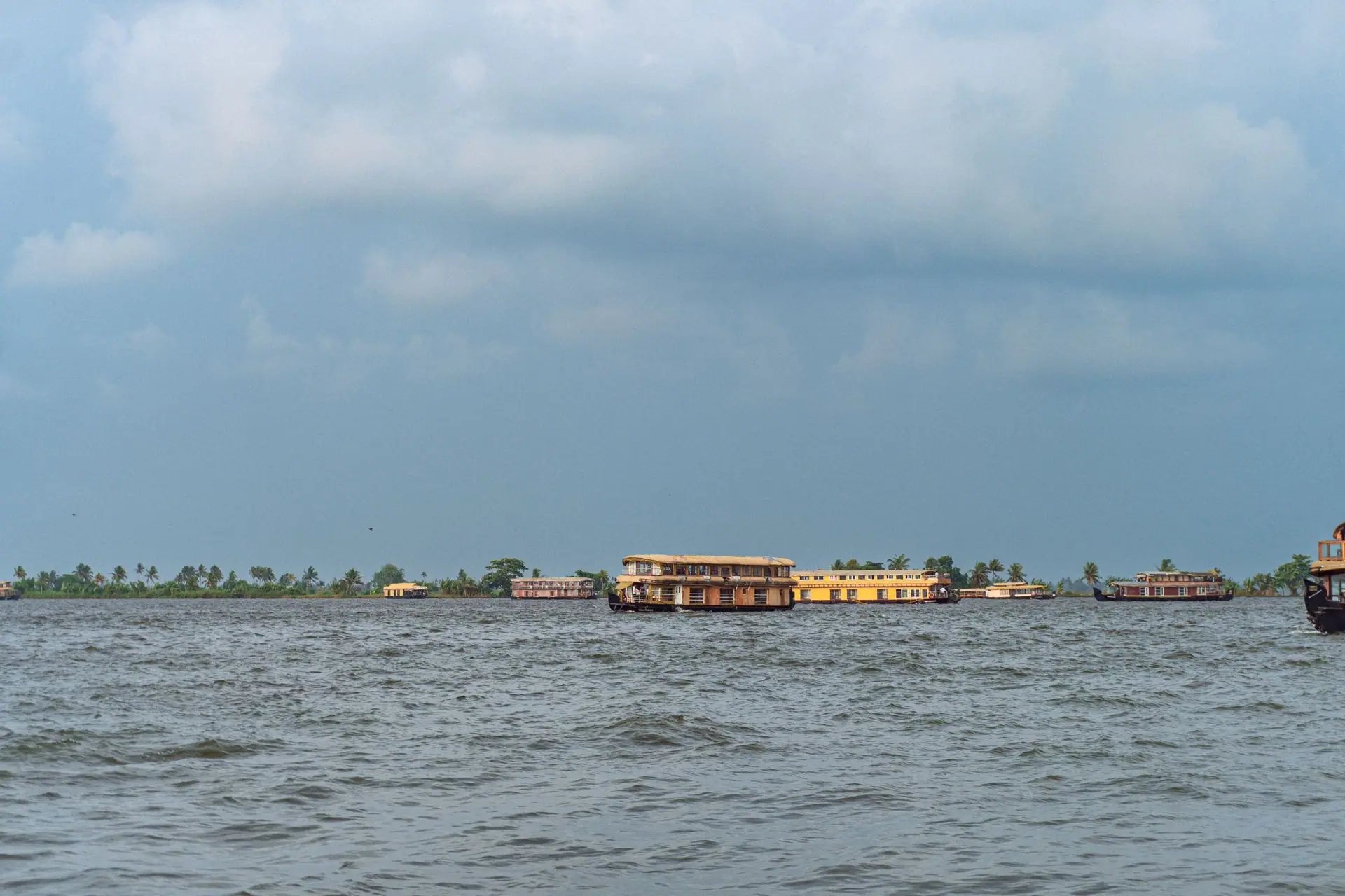 Scenic view of traditional houseboats on Kerala backwaters under a clear blue sky