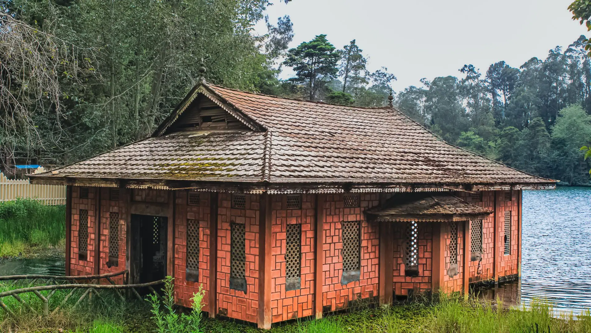 Traditional brick house beside serene lake in lush Kodaikanal landscape