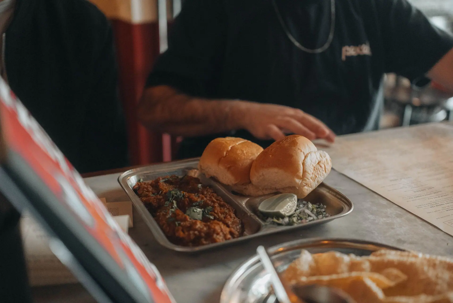 Close-up of pav bhaji dish served with soft buns in an Indian restaurant setting, showcasing street food culture