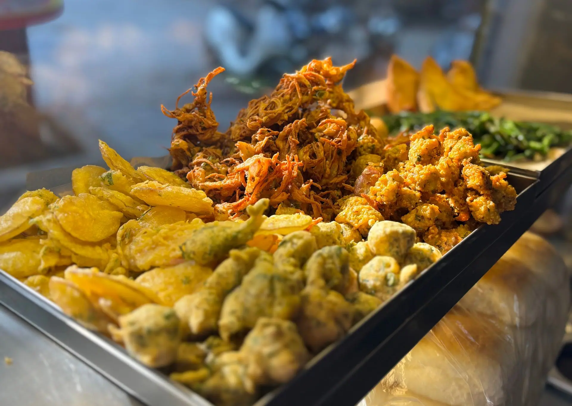 A vibrant display of assorted Indian street food snacks in Mumbai, featuring pakora and bhajia