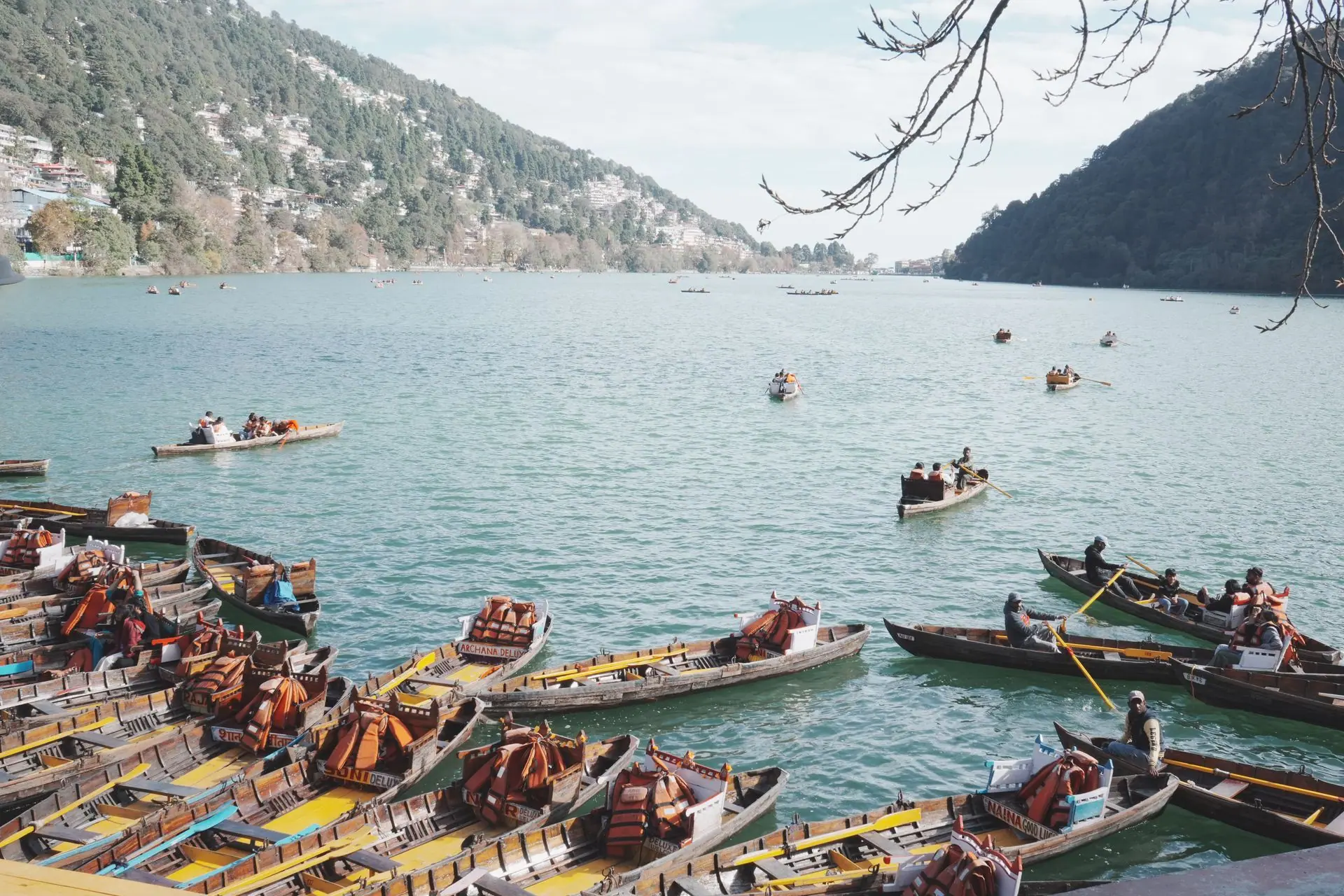 A picturesque scene of boats on Naini Lake, surrounded by lush hills in Nainital, a popular tourist destination