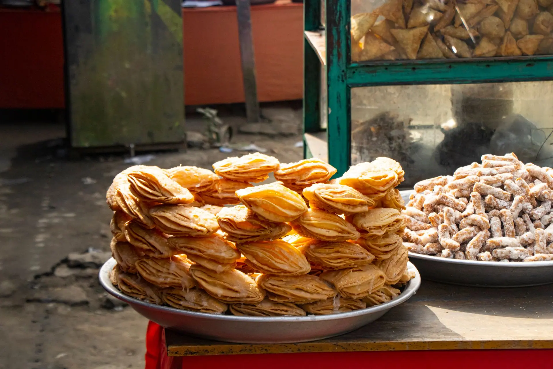 Savoury and sweet Indian street food pastries displayed outdoors. Perfect for traditional snack lovers