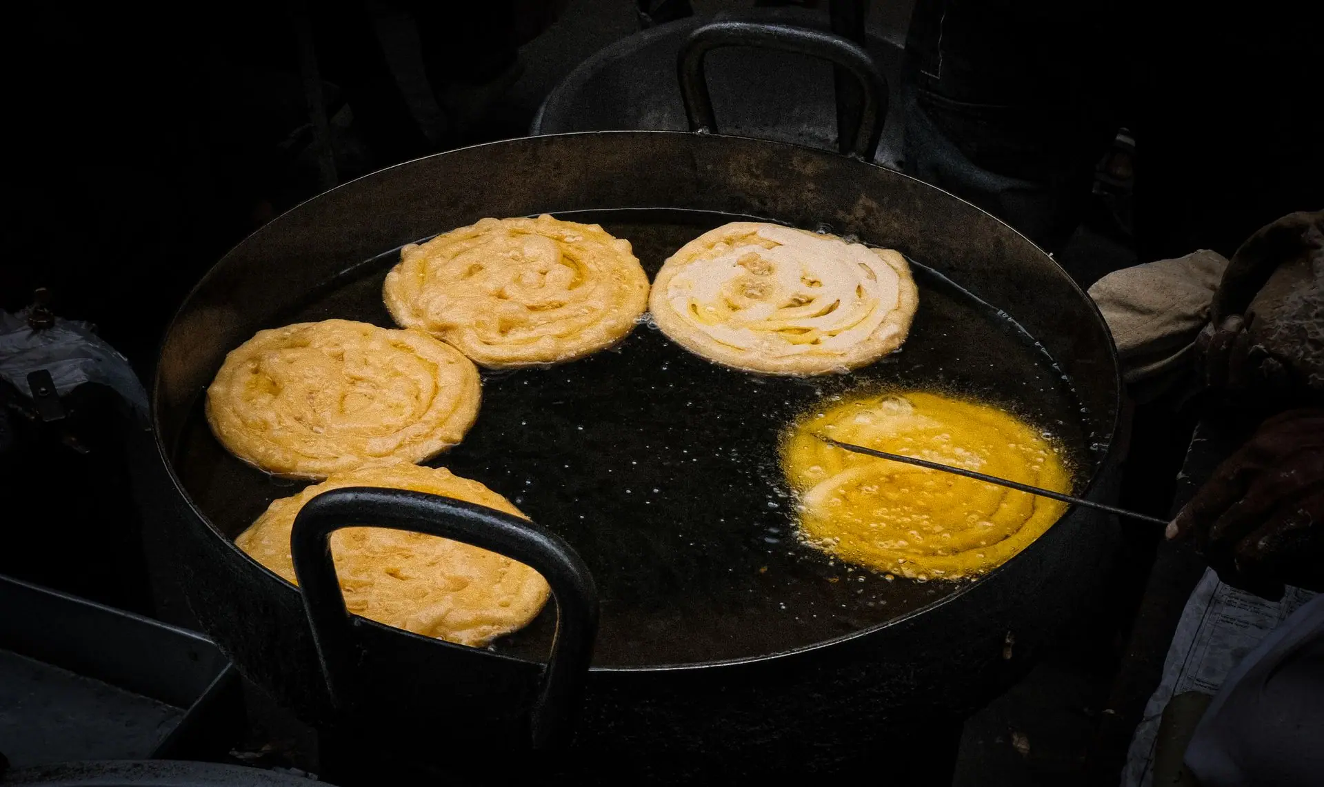 Close-up of crispy Indian jalebi frying in oil, capturing the delicious street food experience