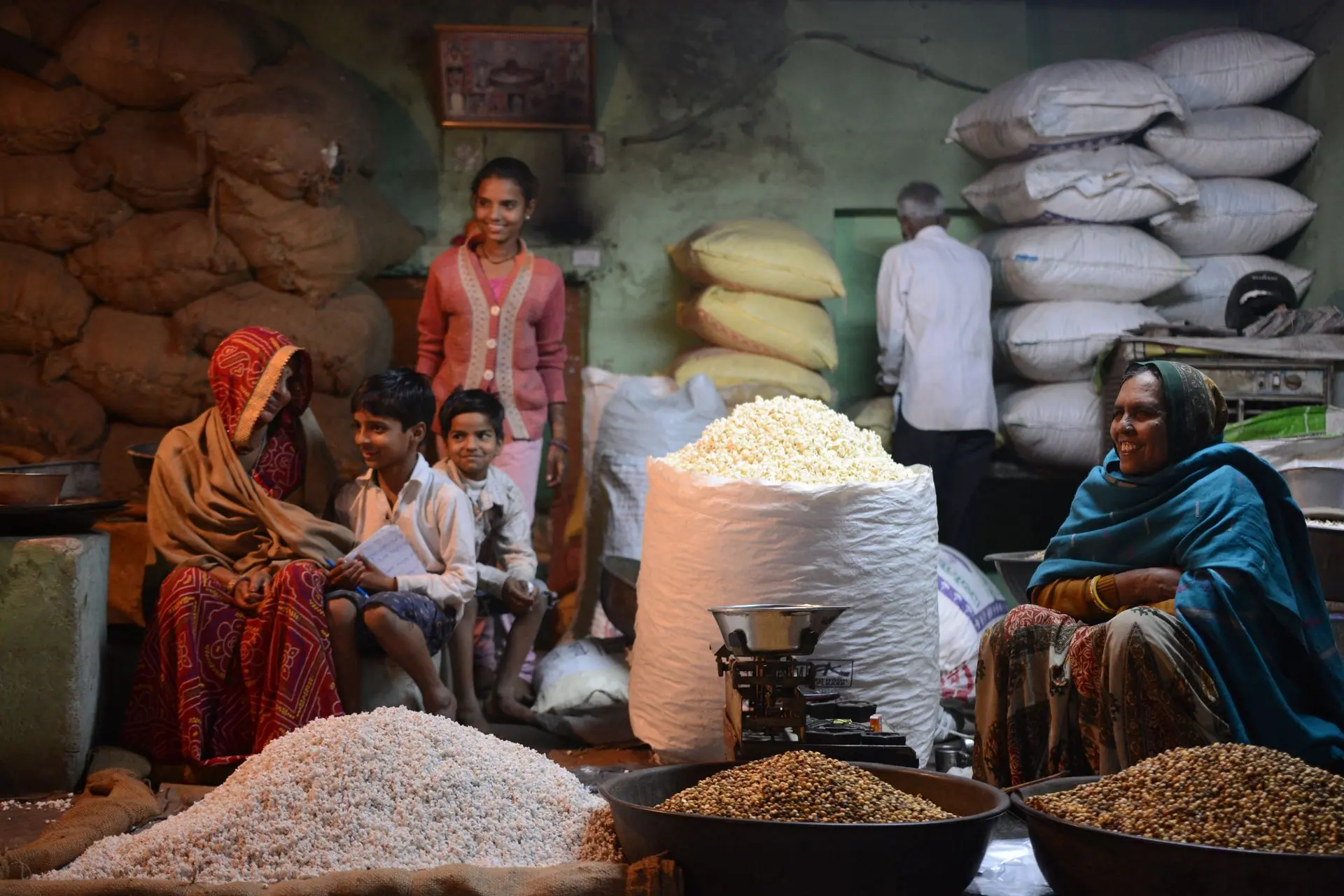 Family vendors selling grains at a busy indoor market in Pushkar, India