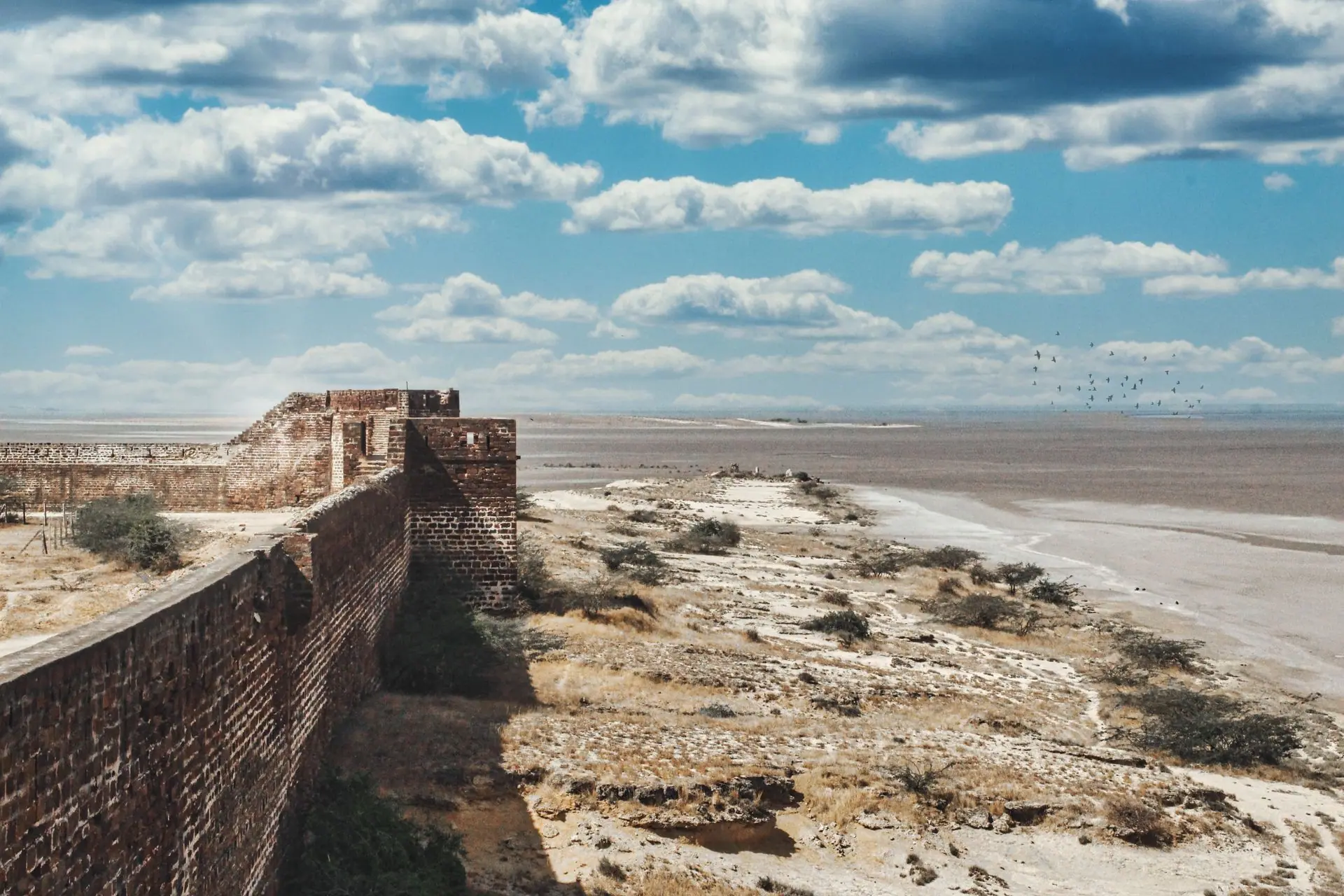 A scenic view of a historic brick fort wall in the arid desert landscape of Kutch, Gujarat