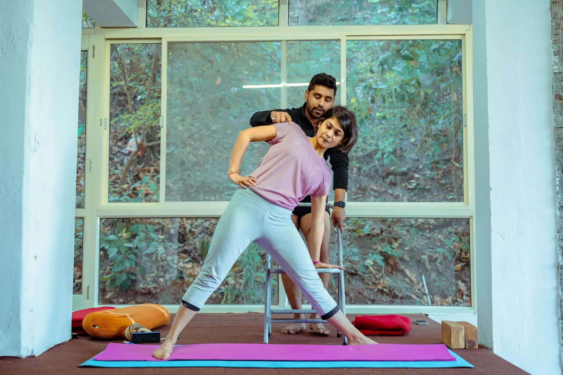 Yoga student stretching with instructor assistance in Rishikesh studio