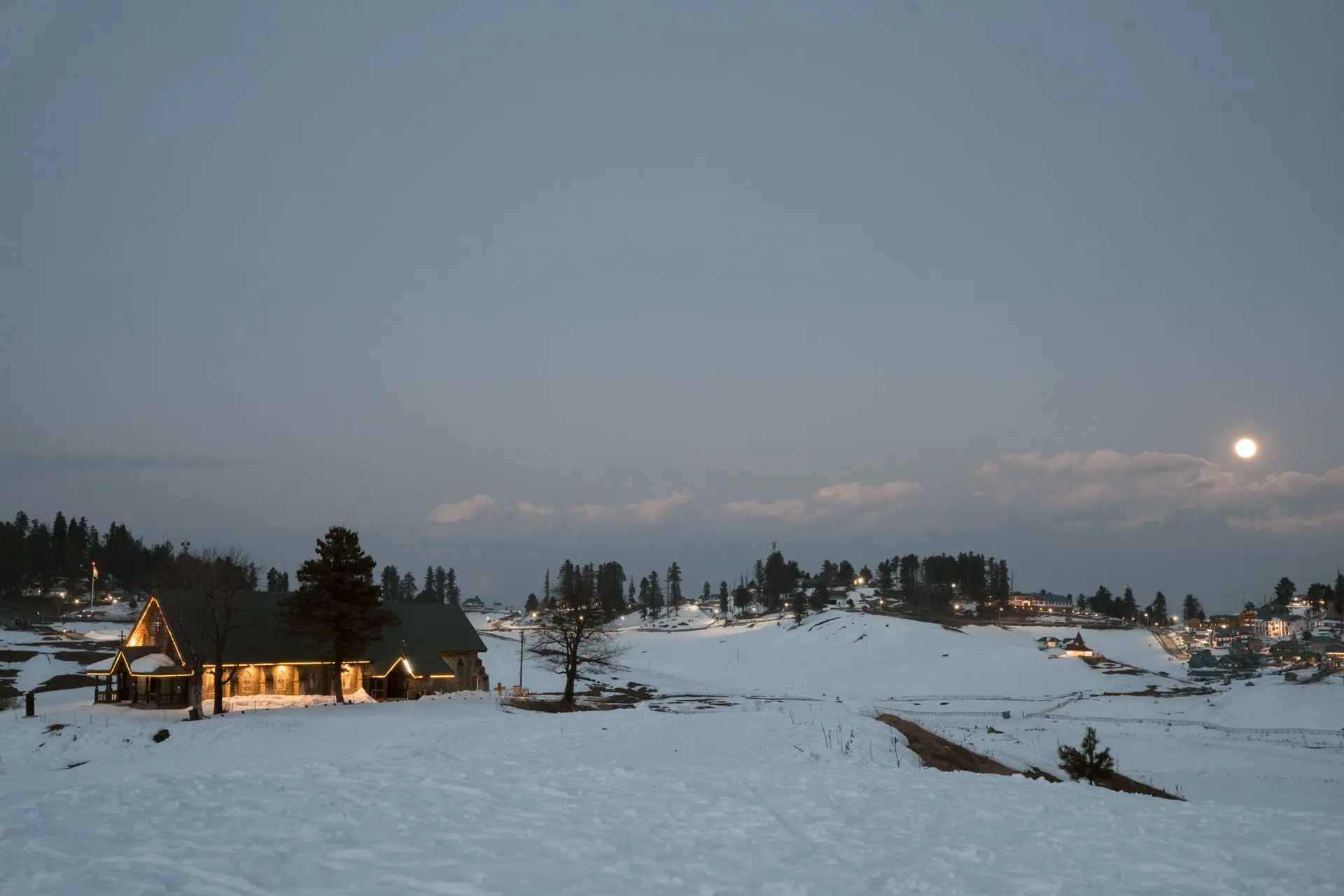 Serene winter night in Gulmarg, Kashmir with a scenic view of snow-covered hills and moonlight