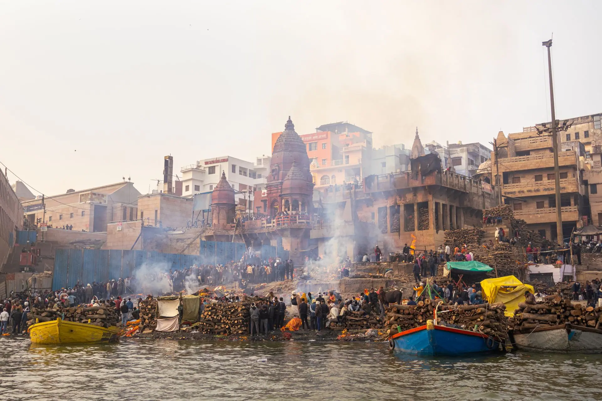A scenic view of Varanasi Ghat along the Ganges with traditional cremation rituals at sunset