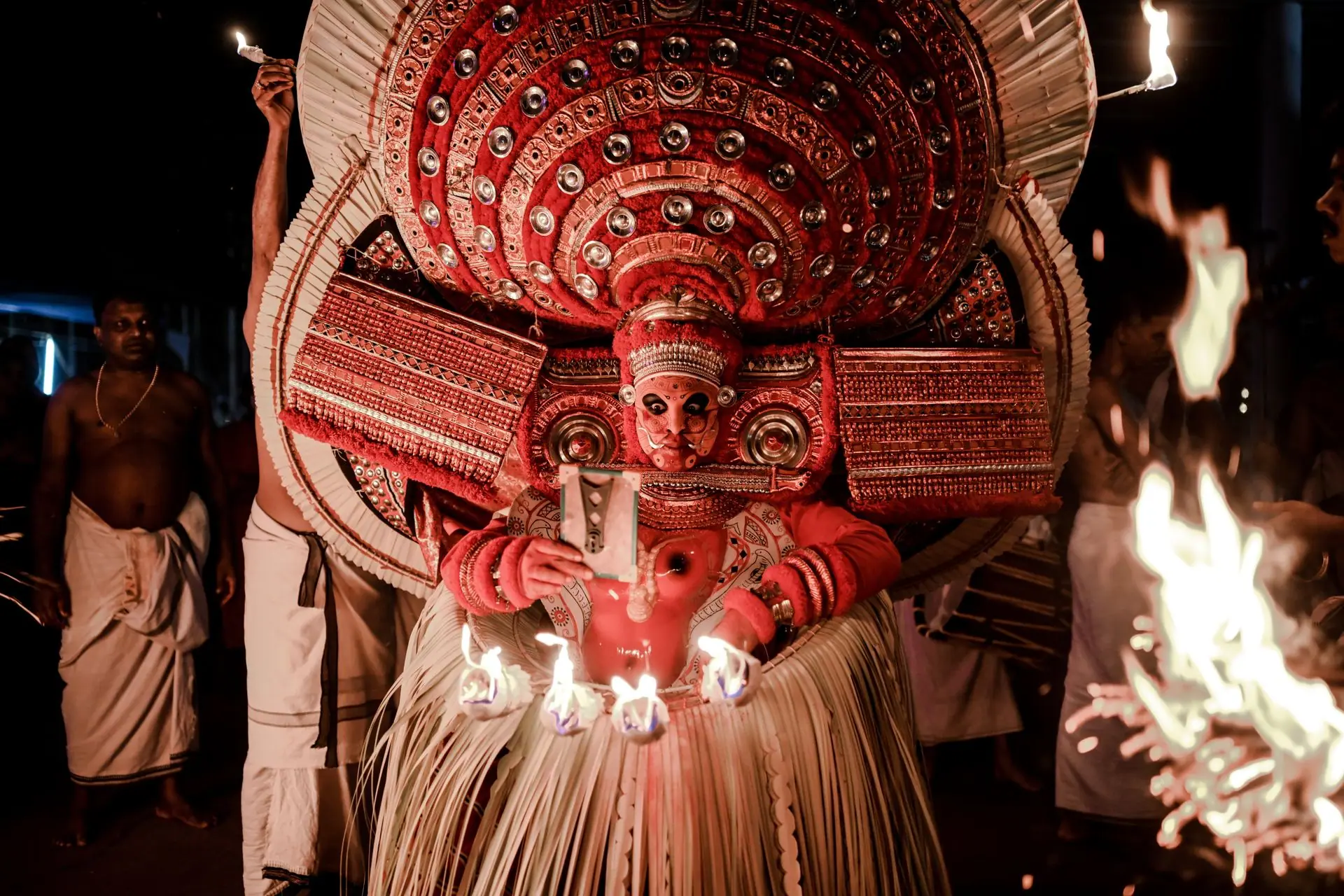 A vibrant Theyyam ritual with intricate costume and fire, capturing cultural heritage