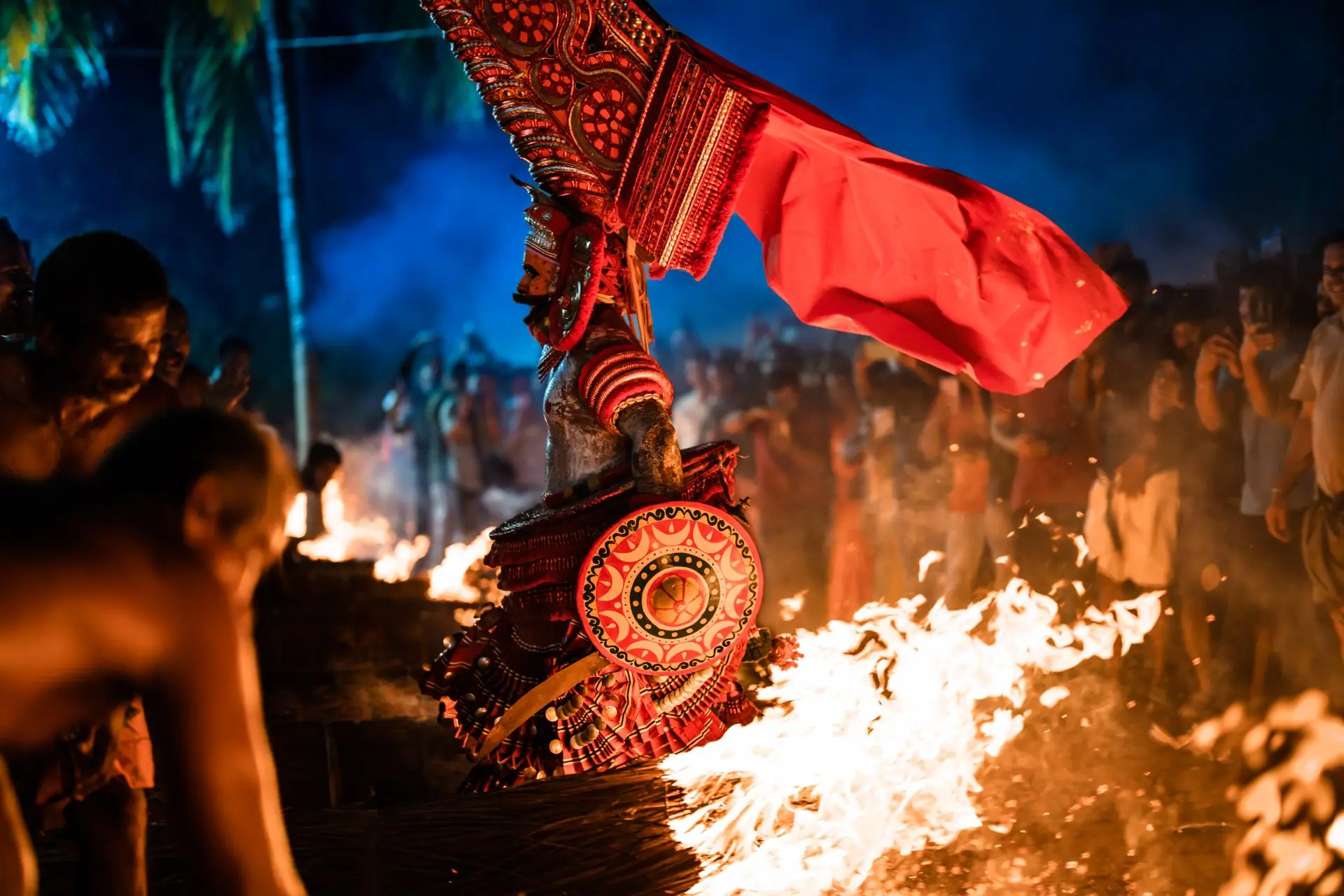 A vivid portrayal of Theyyam ceremony in Udinur, India, amidst fire and vibrant costumes at night
