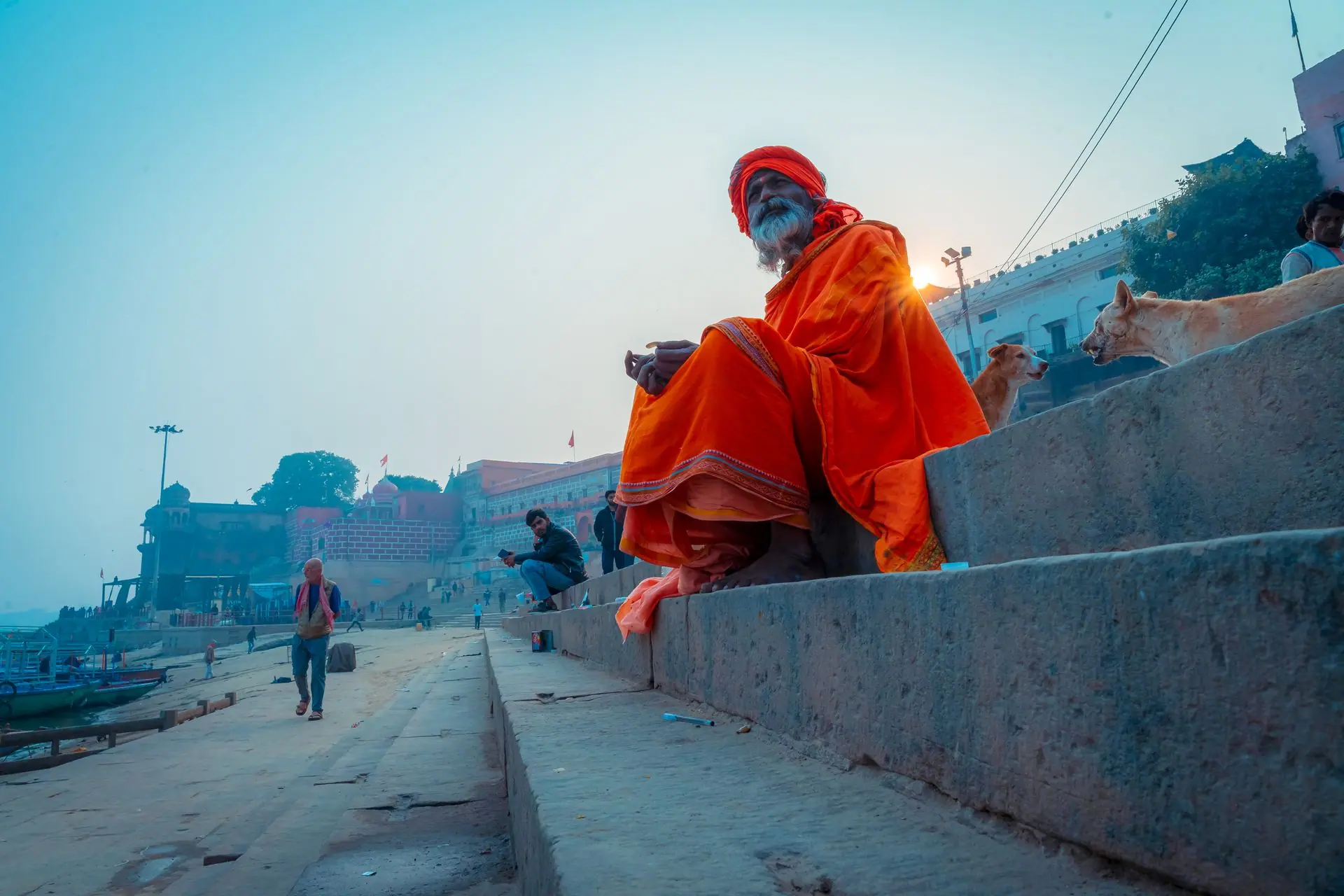 A holy man sits on the steps of Varanasi Ghats with the morning sun rising behind him, capturing the spiritual essence