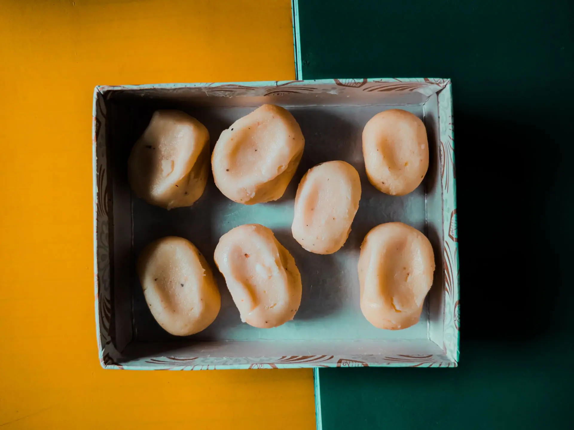 Aerial view of Indian sweets arranged in a decorative box on a colorful background