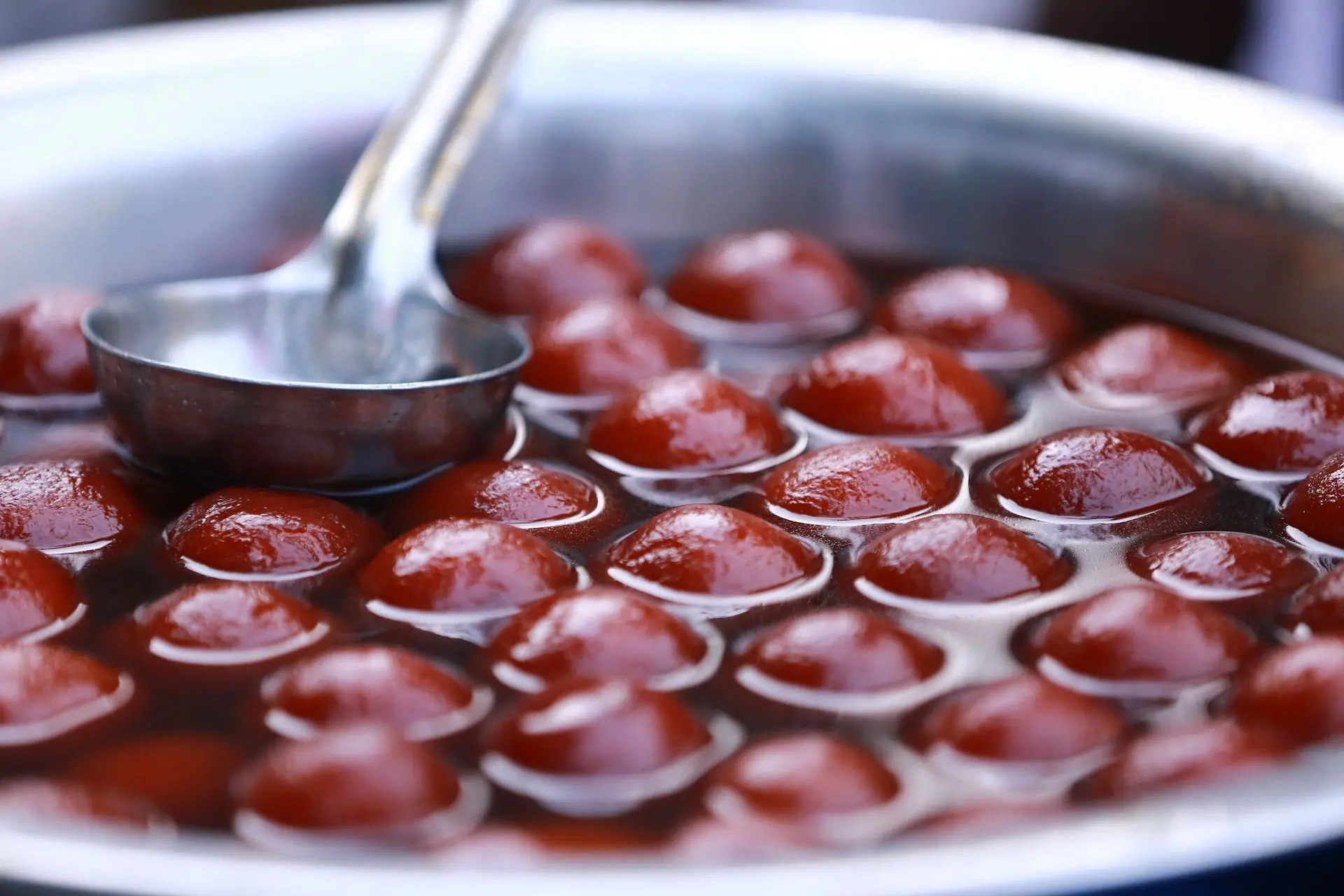 Close-up view of Gulab Jamun in a stainless steel pot, popular Indian dessert street food
