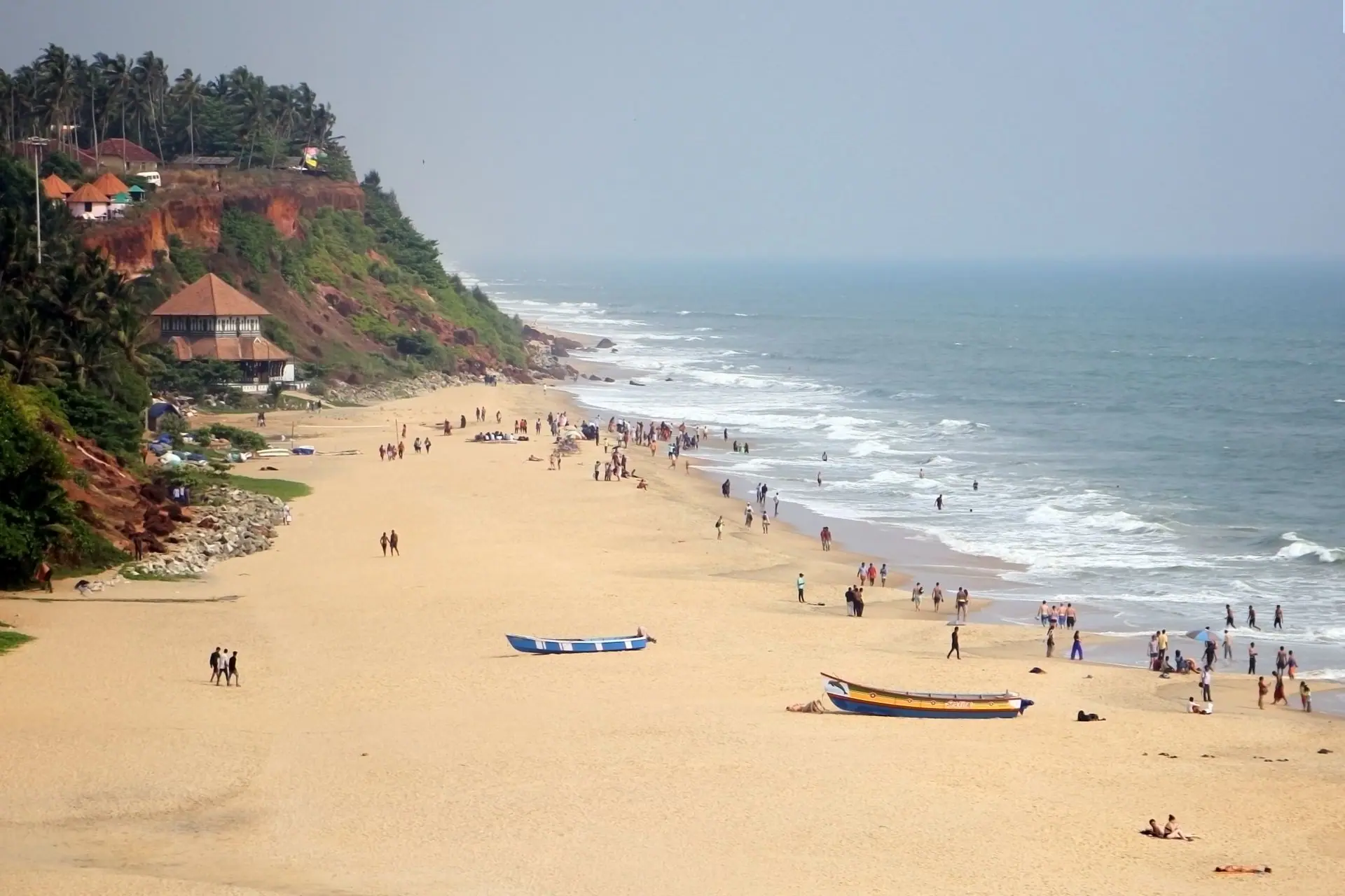 Varkala Beach with cliffs, boats, and people enjoying the sunny day by the sea