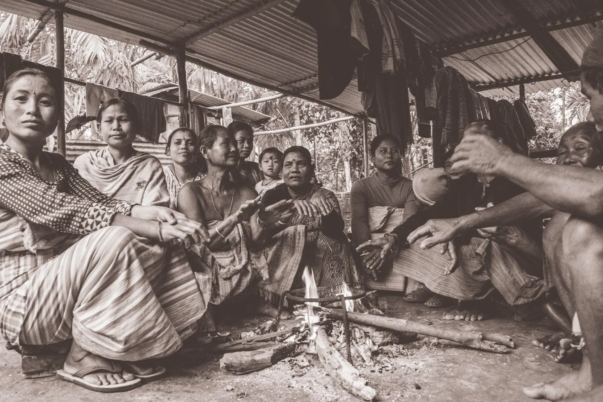 A tribal community gathered indoors in Assam. Captured in warm grayscale, it showcases their culture and traditions